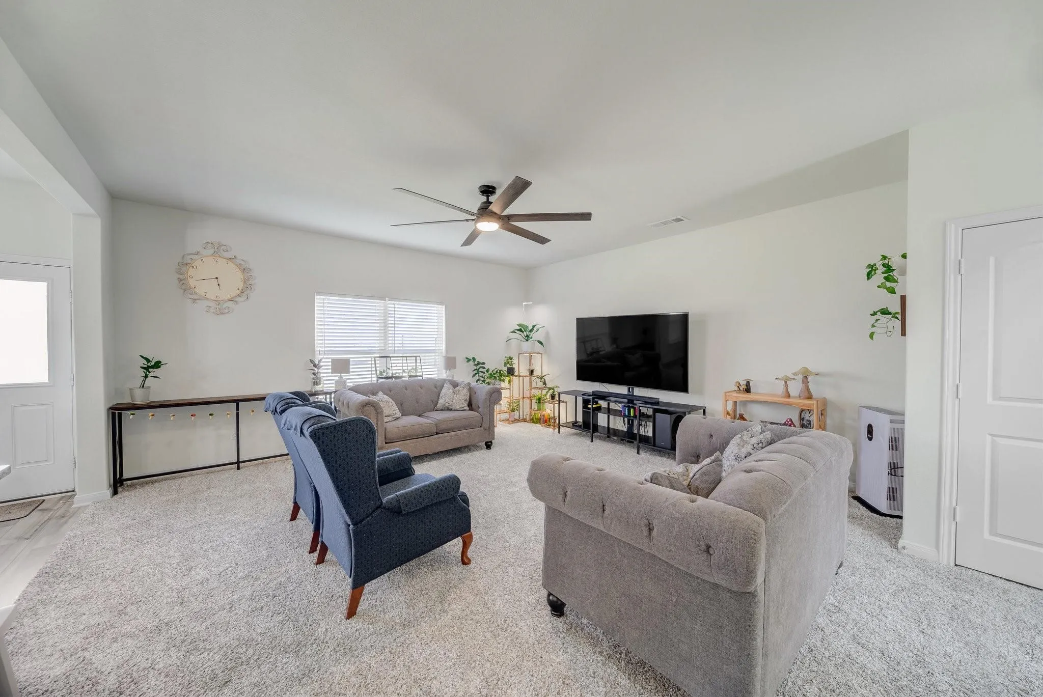 Spacious living area featuring light-toned carpeting and neutral wall tones