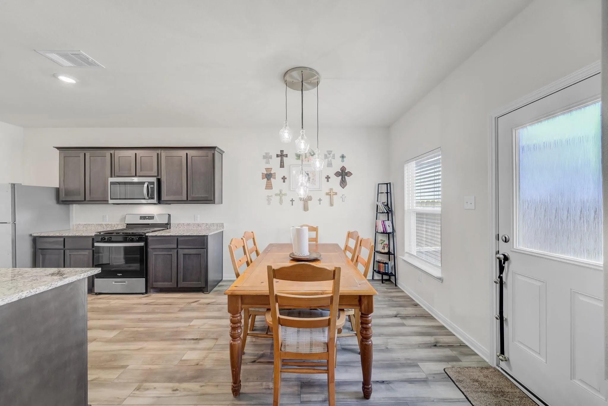 Open-concept kitchen and dining area featuring wood-finish flooring, dark wood cabinetry, and light-toned countertops