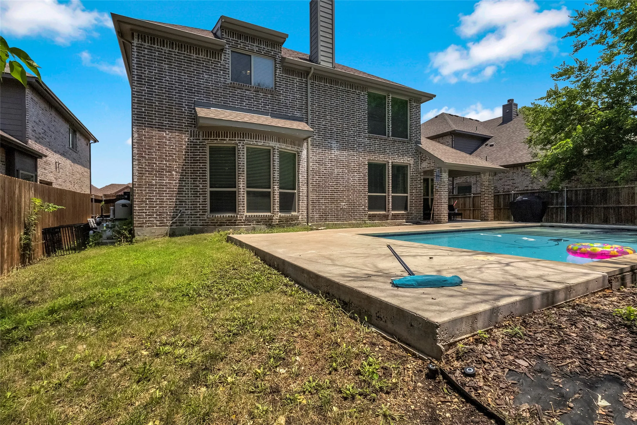 Backyard with a rectangular swimming pool, concrete patio, and a covered porch