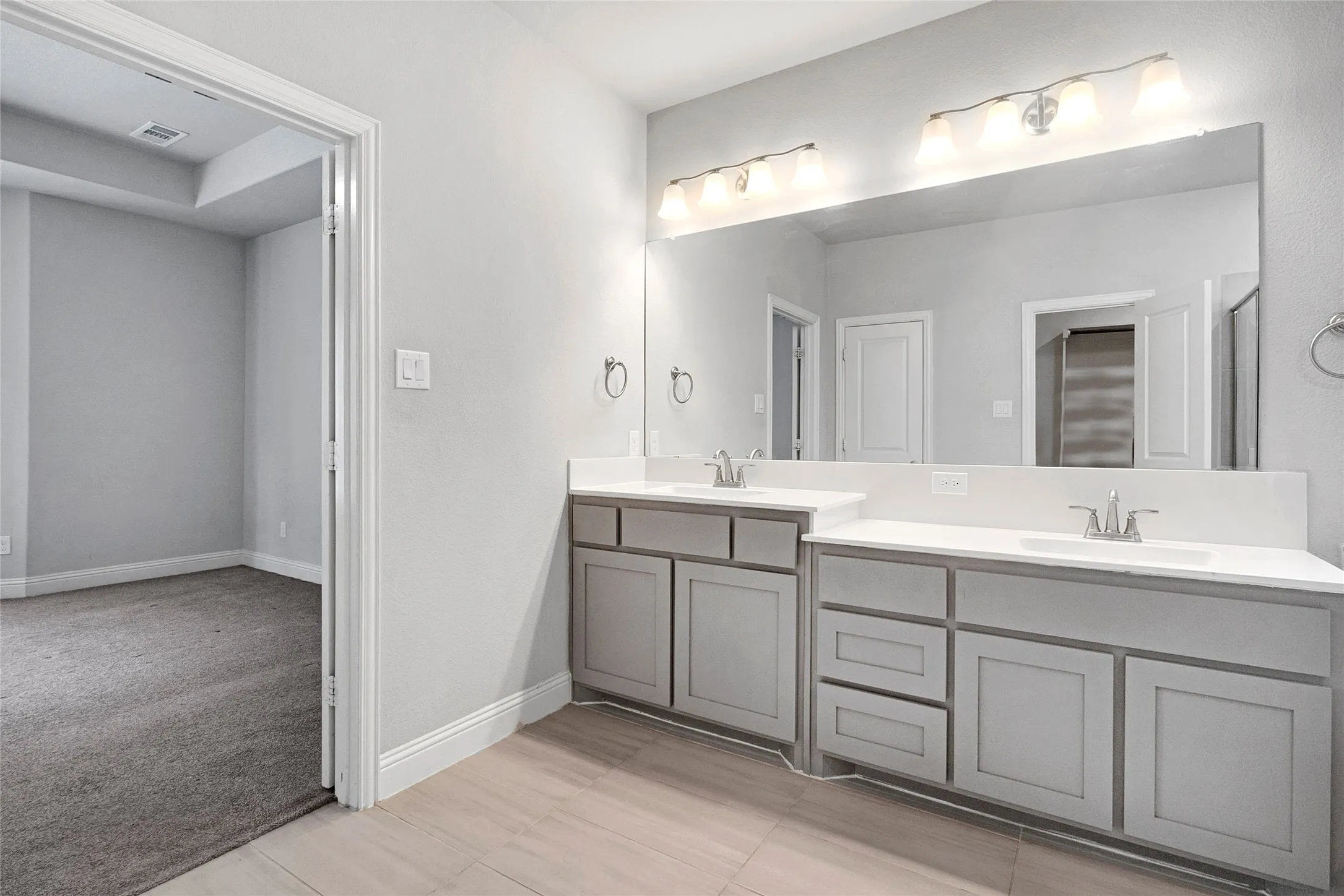 Double vanity featuring light gray cabinetry, integrated sinks, and polished chrome faucets