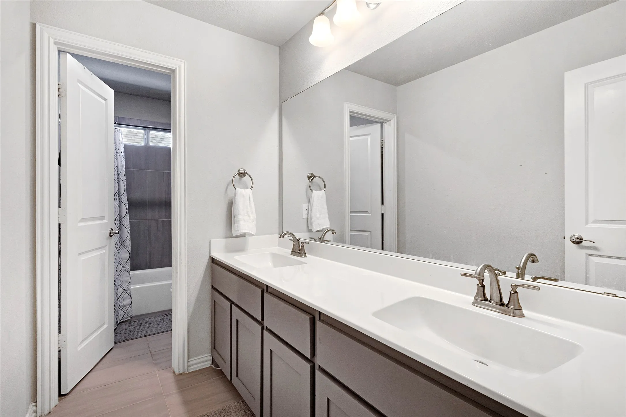 Bathroom vanity featuring a dual sink, integrated countertop, and brushed nickel fixtures