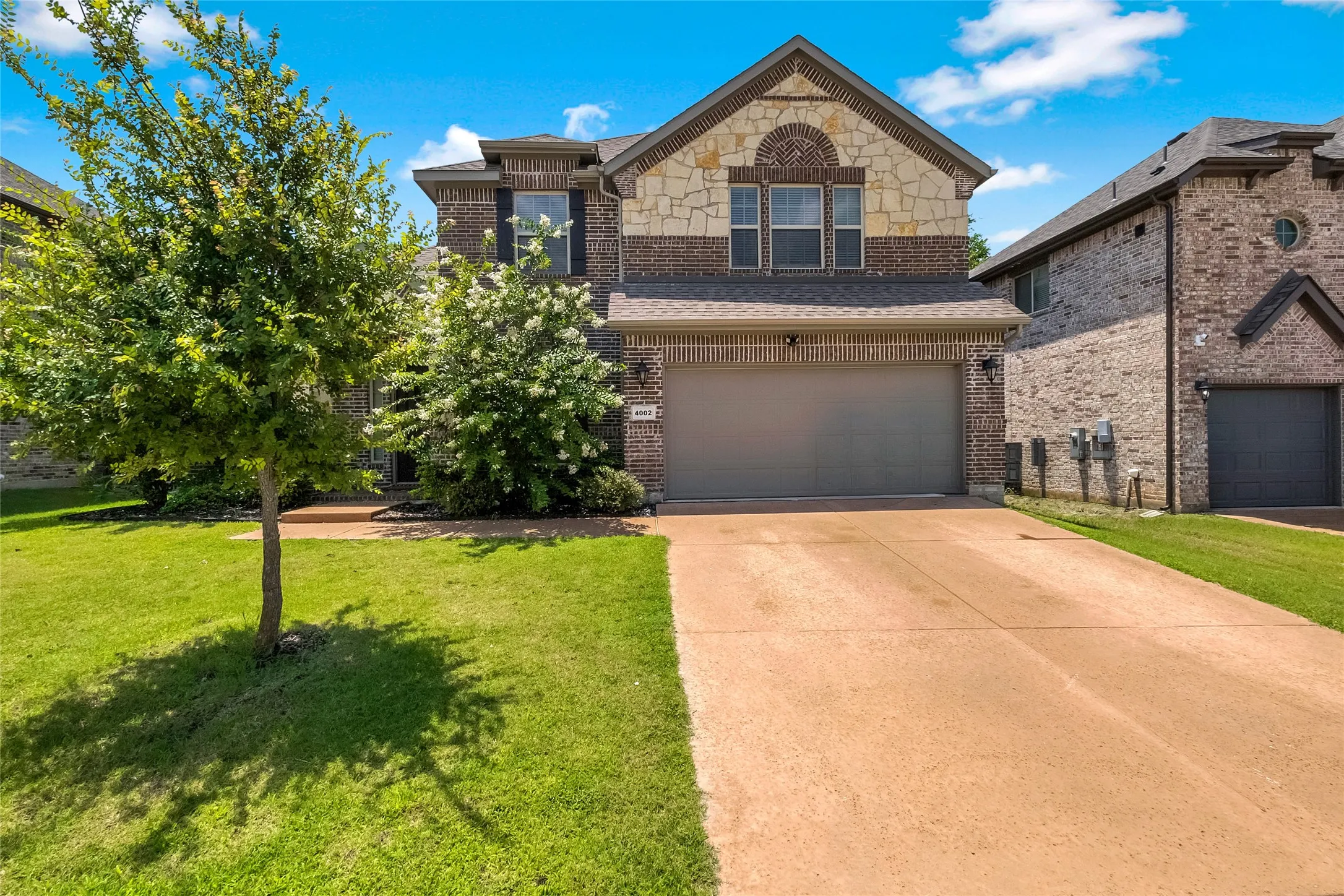 Two-story brick and stone facade residence featuring an arched stone accent over the second-story windows