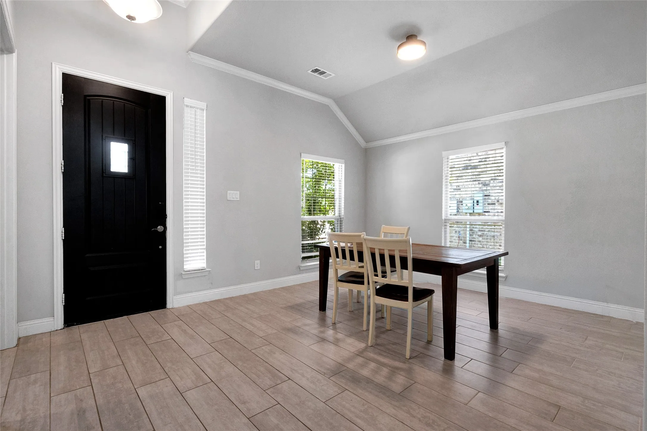 Entry area featuring a dark paneled door with a rectangular window, wood-finish flooring, and light gray walls