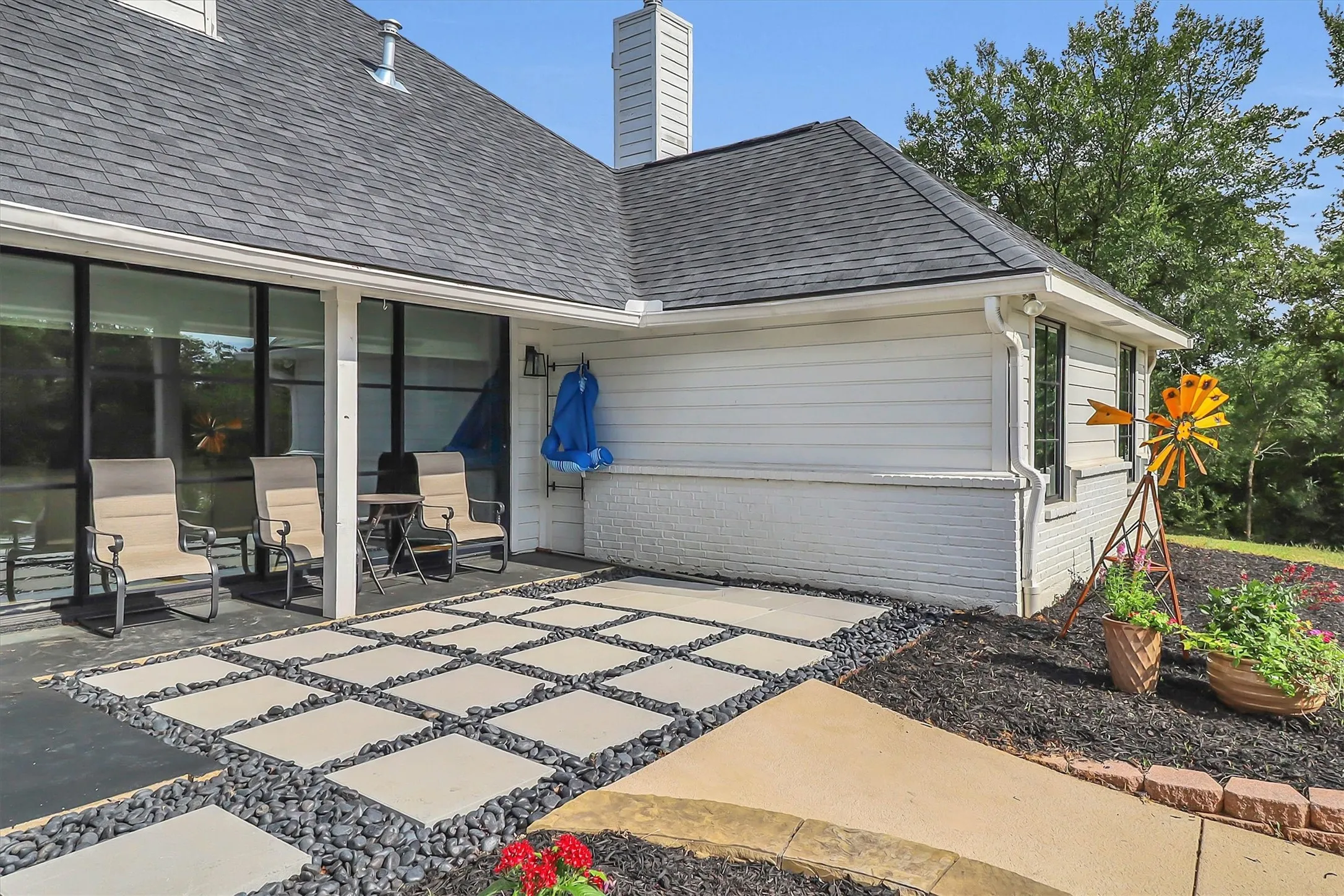 Expansive outdoor patio featuring large square pavers with dark pebble infill