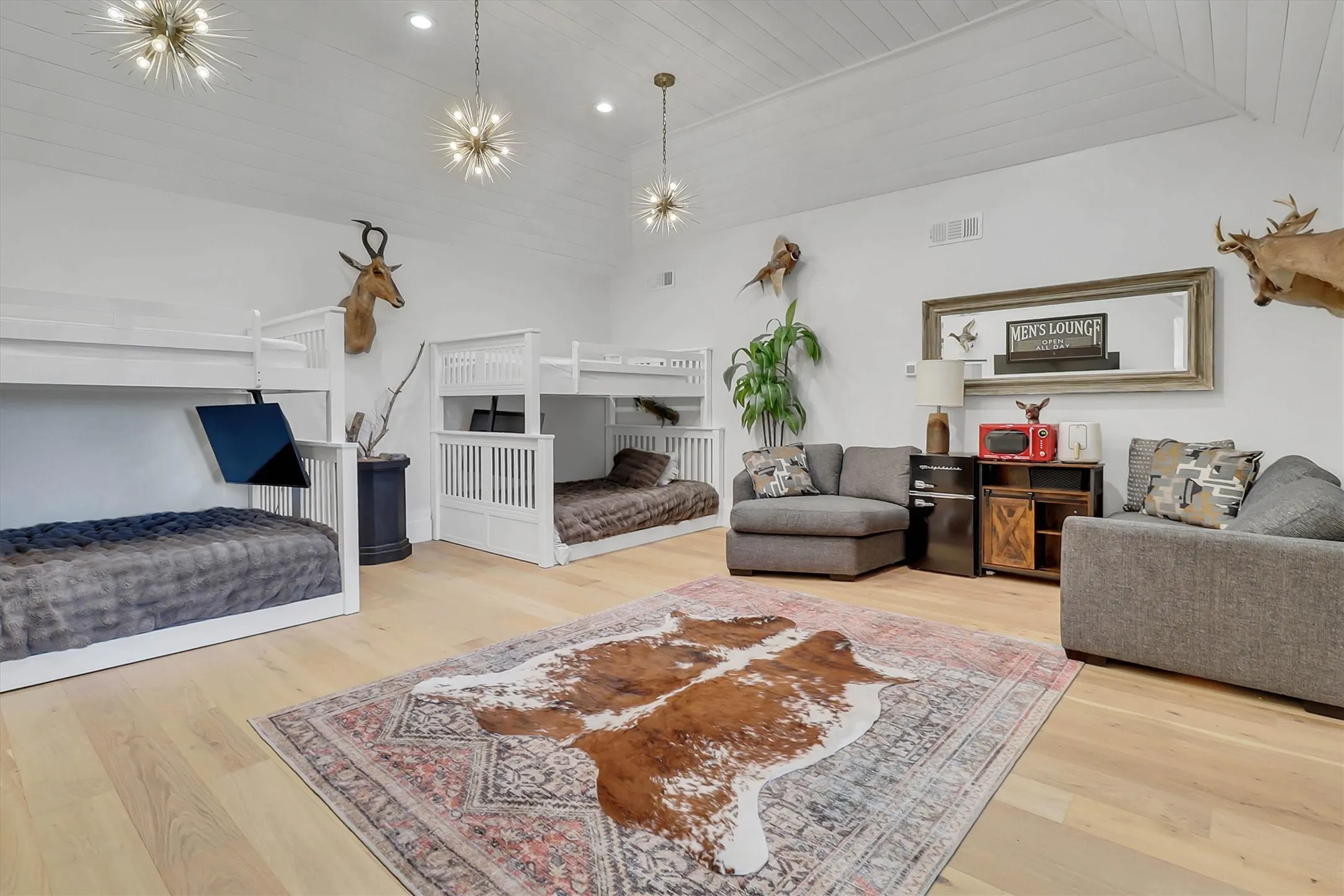 Spacious room featuring light wood-finish flooring, white shiplap ceiling, and multiple starburst pendant light fixtures