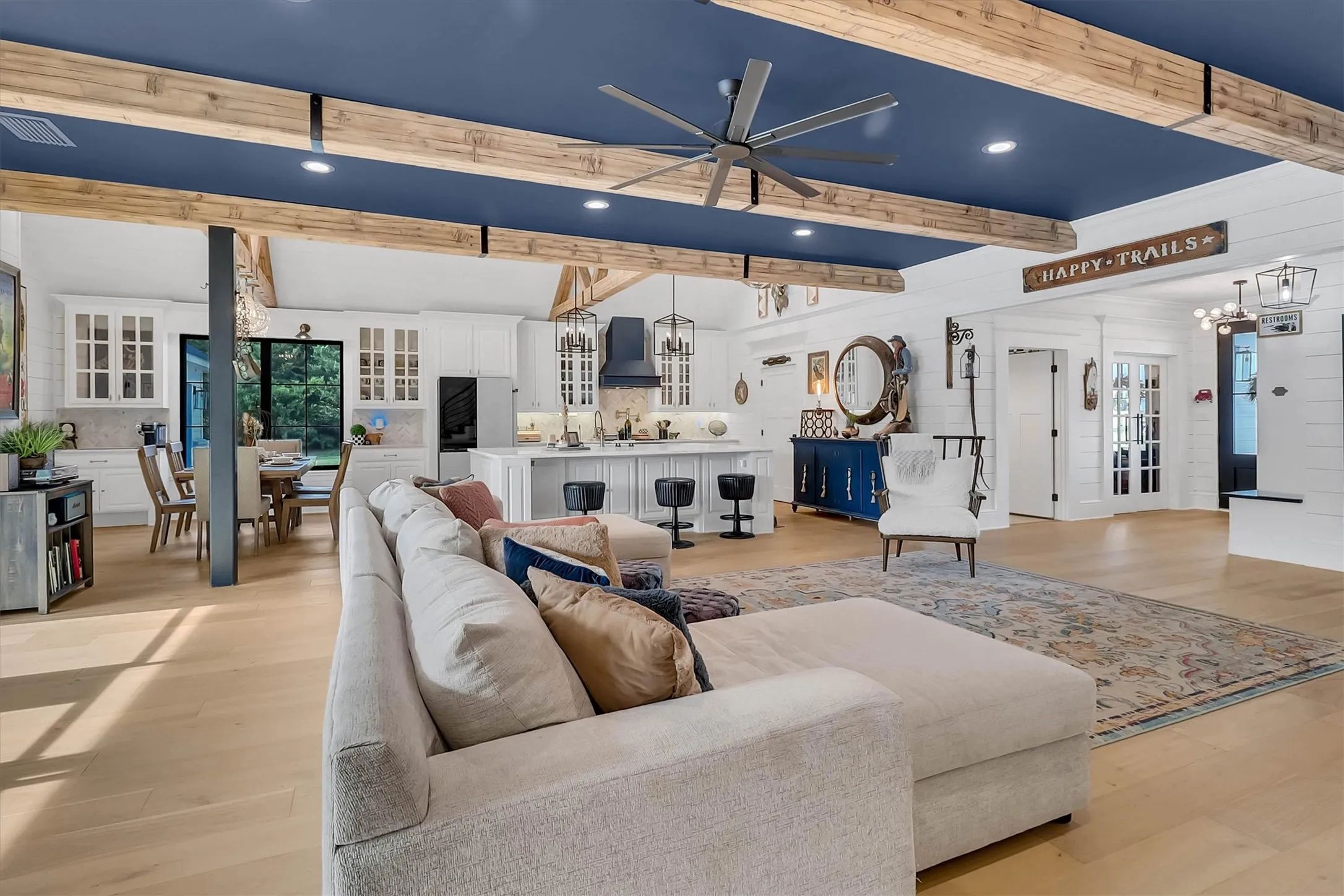 Open-concept living space with light wood-finish flooring and a distinctive blue ceiling with exposed wood beams