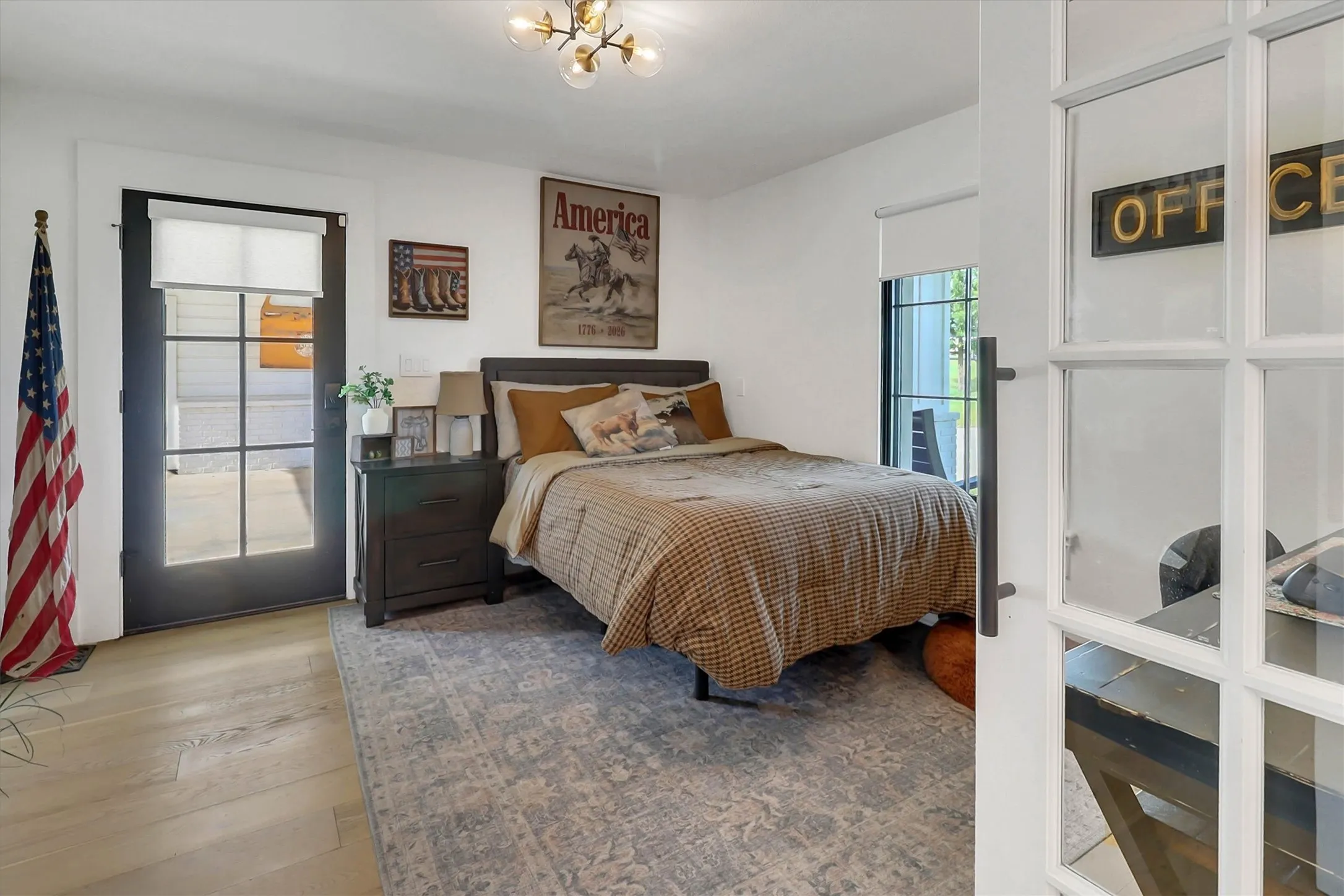 Bedroom featuring a glass-paned exterior door, light wood-finish flooring, and a modern chandelier