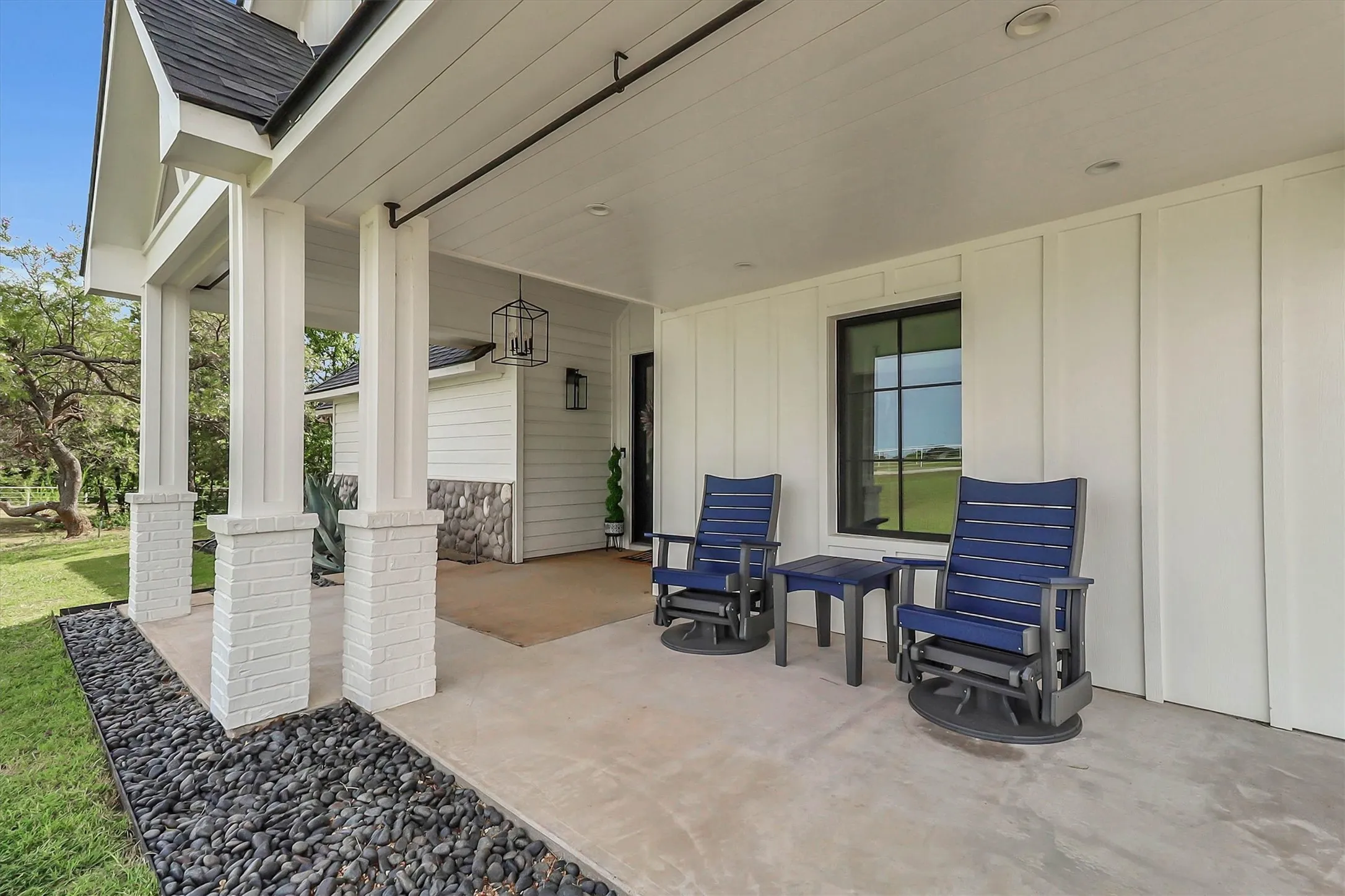 Covered front porch featuring white board and batten siding and stone accents