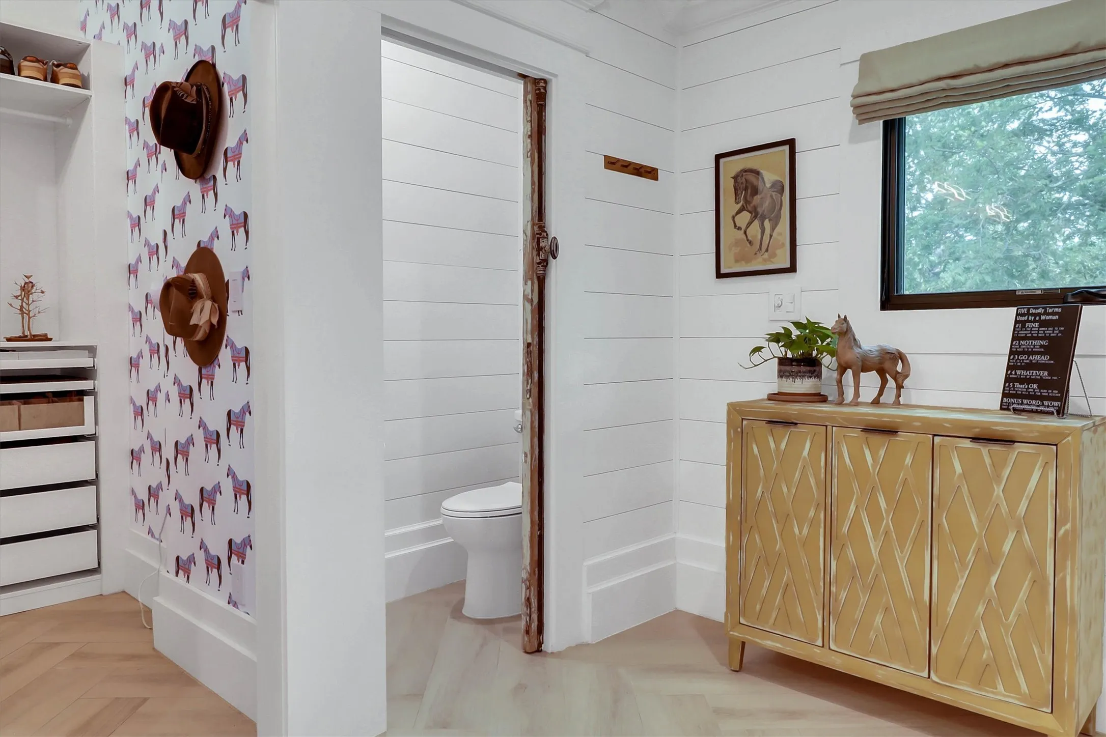 Herringbone wood-finish flooring in a bright area featuring shiplap walls and a window with natural light