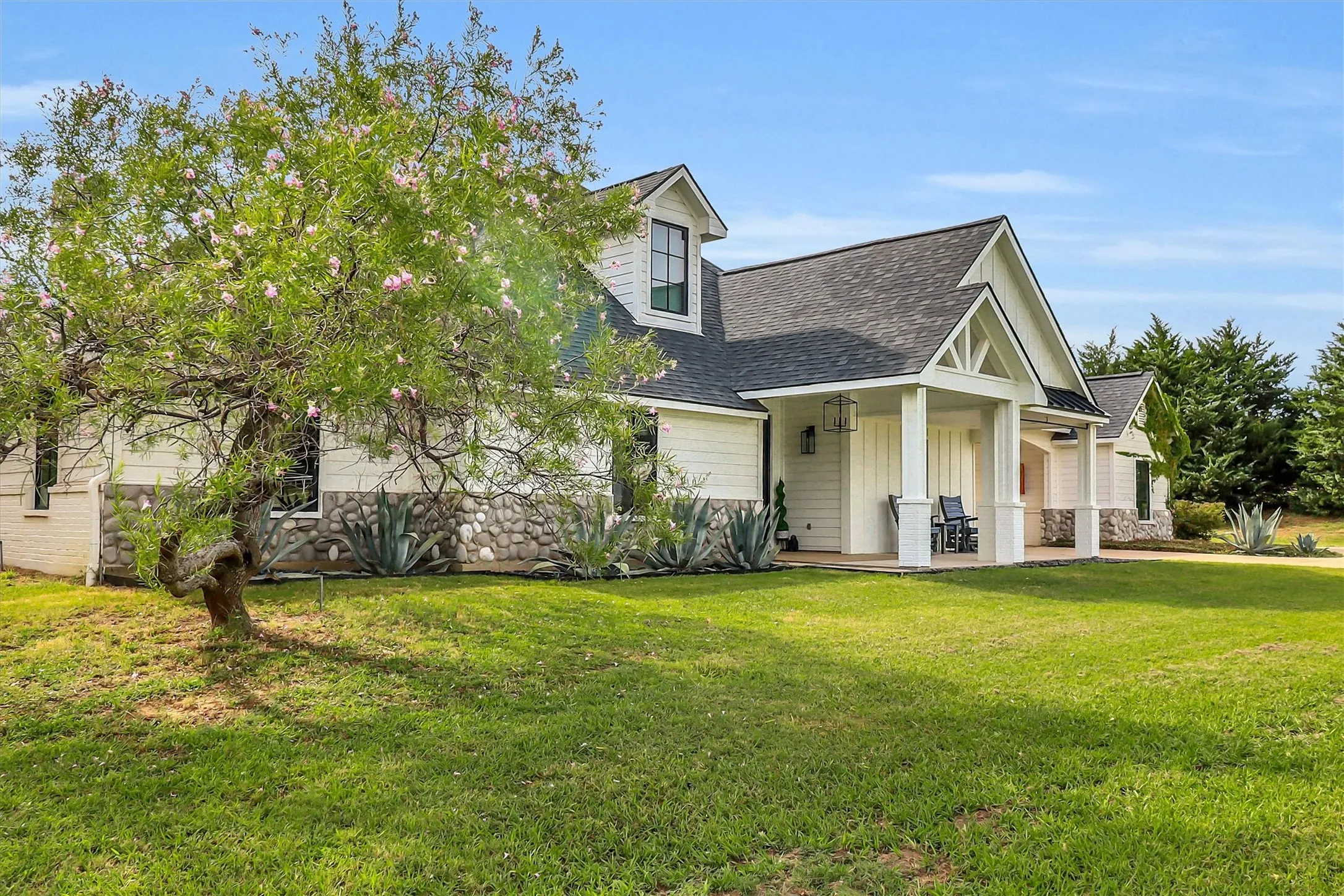 White siding exterior featuring stone accents and a covered front porch with white columns