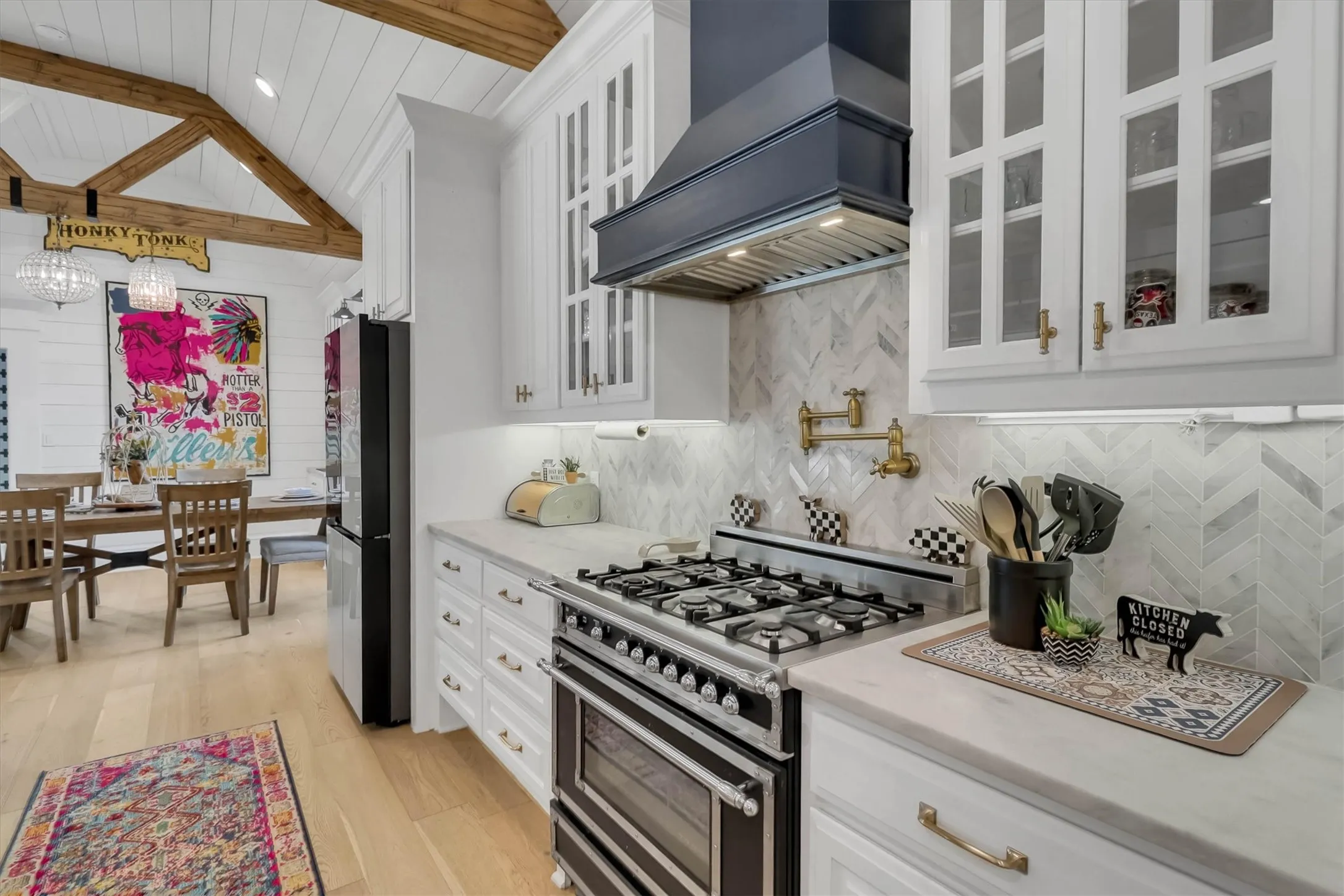 Kitchen featuring a professional-grade range, white cabinetry with glass inserts, herringbone tile backsplash, and a wall-mounted pot filler