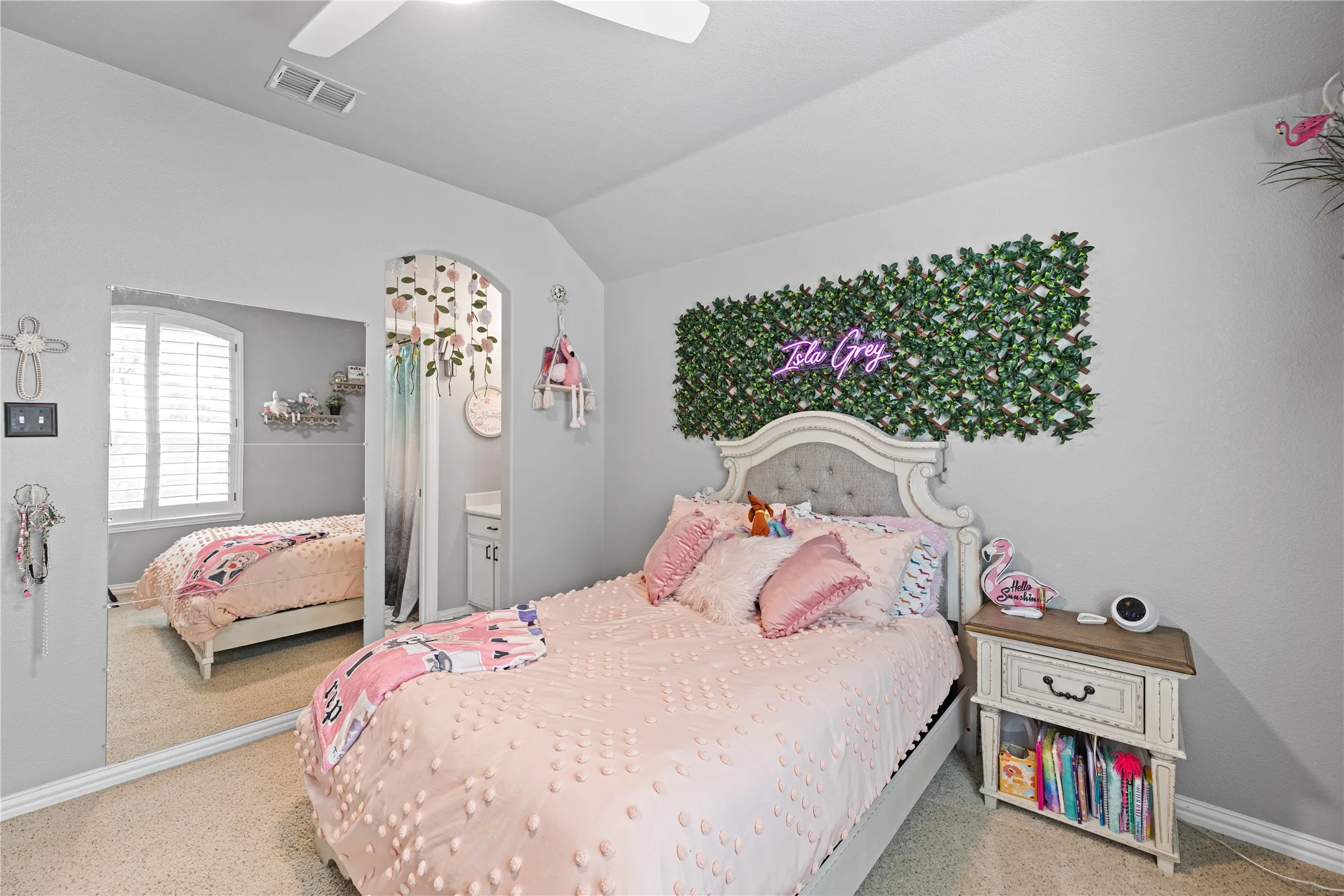 Carpeted room with a ceiling fan, arched doorway, and built-in window shutters