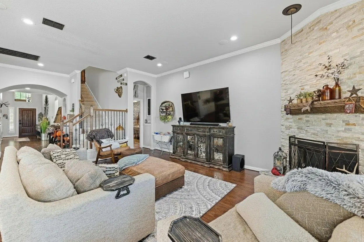Living room with hardwood-finish flooring, recessed lighting, and a stone-clad fireplace featuring a wood mantle
