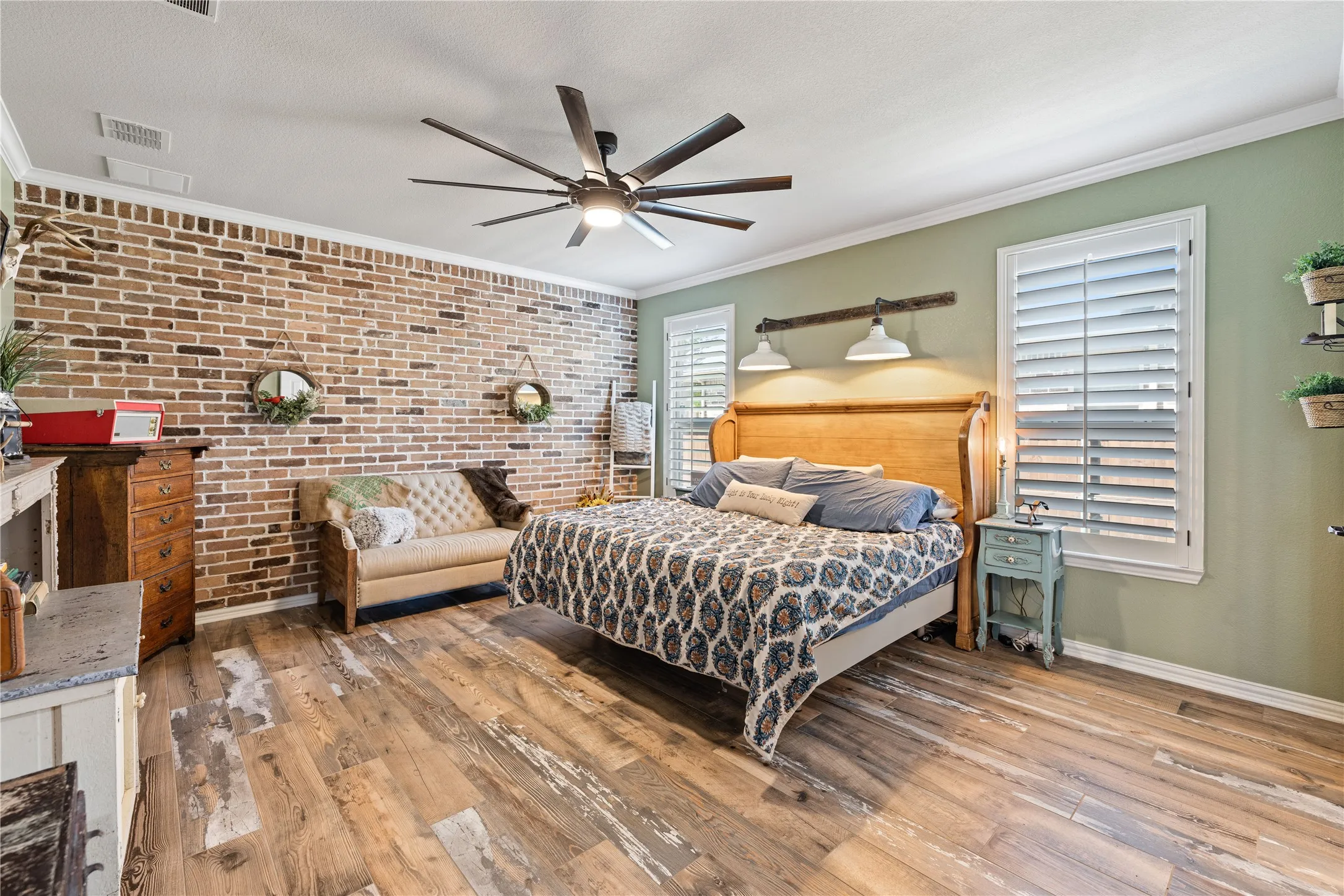 Bedroom with ceiling fan, crown molding, brick wall, a textured ceiling, and light wood-type flooring