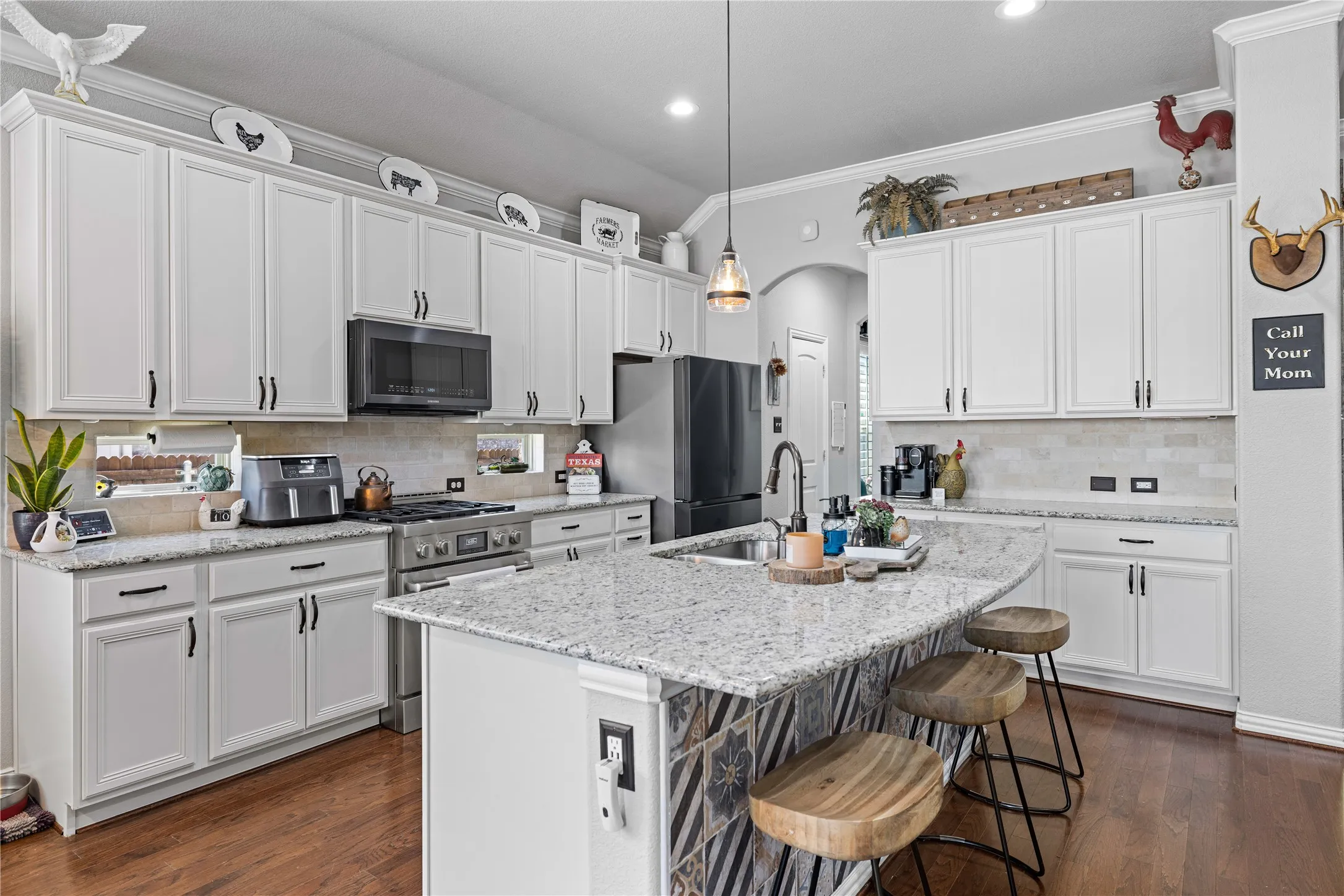 Kitchen with decorative light fixtures, crown molding, stainless steel appliances, and dark wood-type flooring