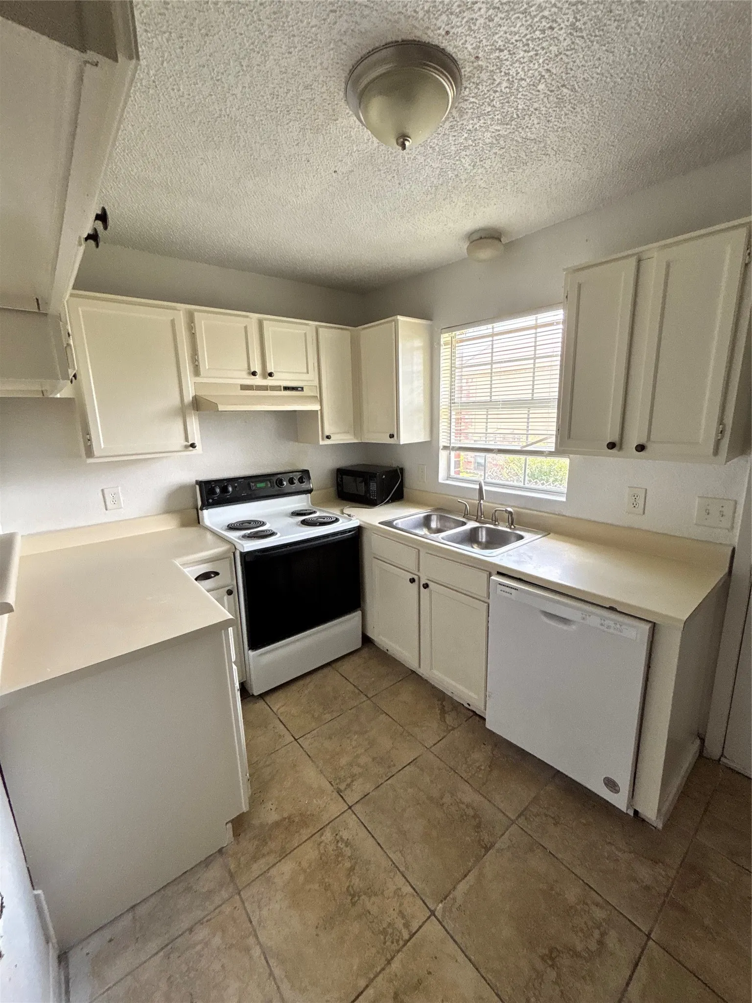 Kitchen featuring light-toned cabinetry, a double basin stainless steel sink, and a white electric range