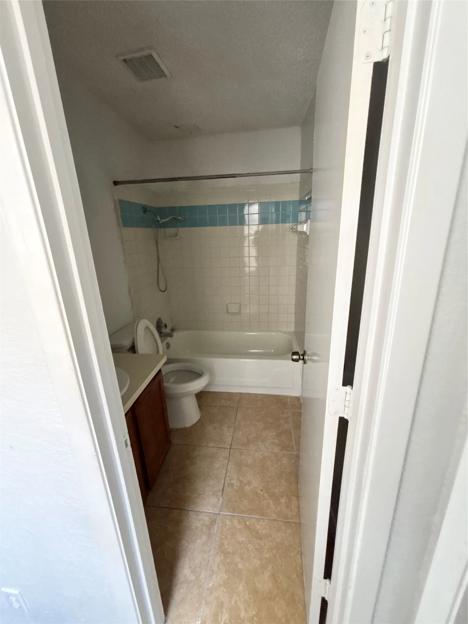 Bathroom featuring a tub/shower combination with white tile surround and blue accent band