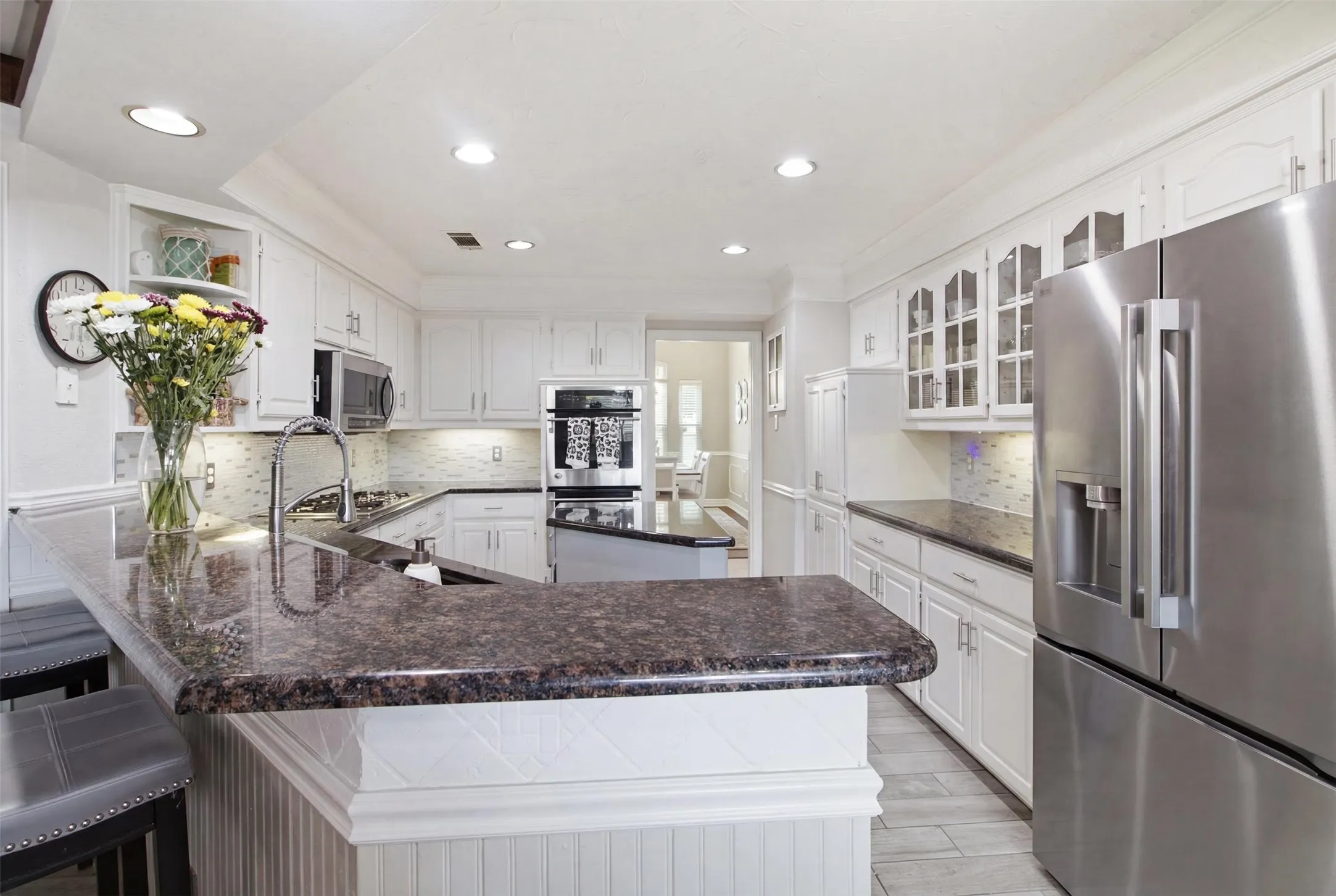 Kitchen featuring white cabinetry, dark granite countertops, stainless steel appliances, recessed lighting, and a patterned tile backsplash
