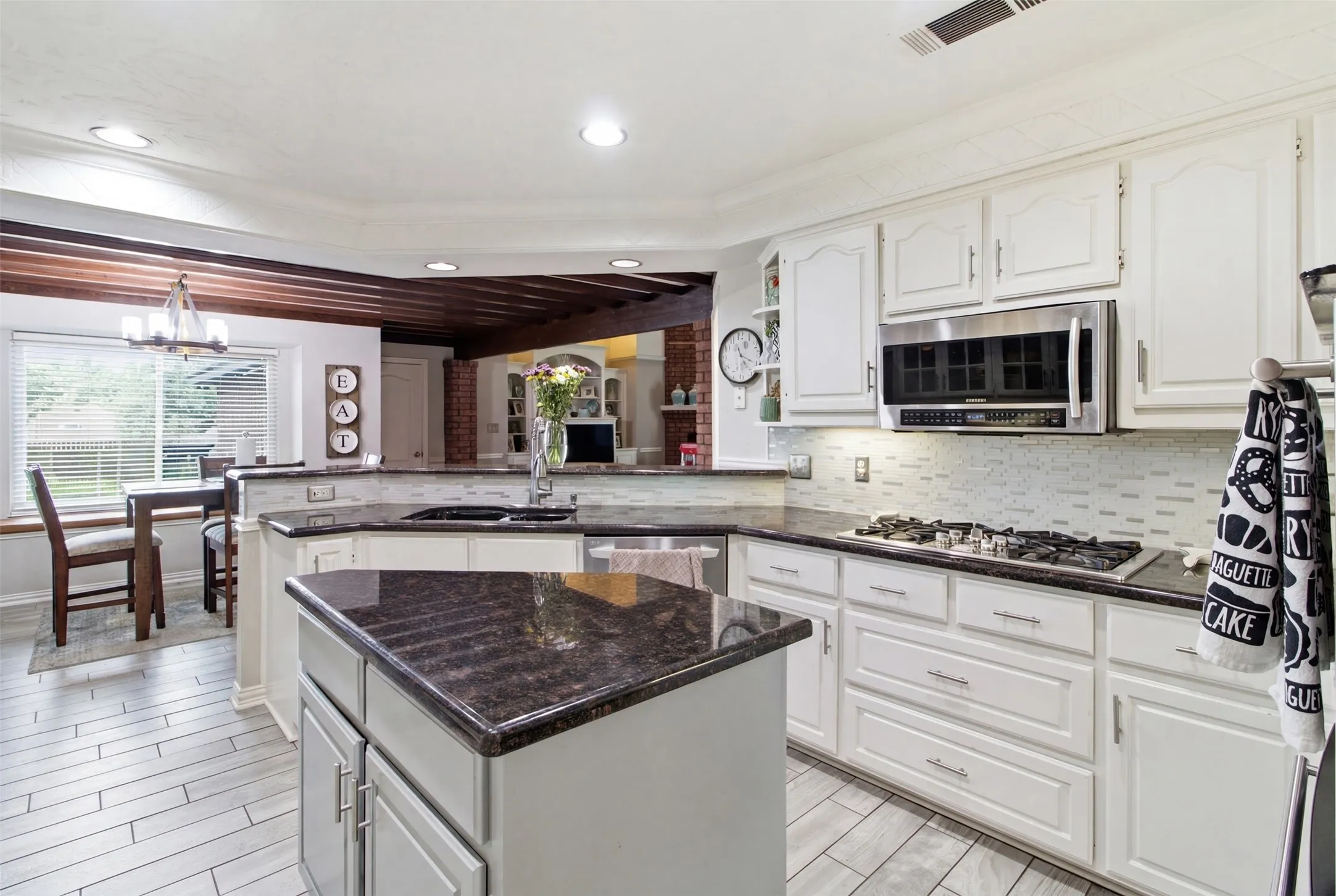 Kitchen featuring white cabinetry, dark granite countertops, stainless steel appliances, a gas cooktop, and light-toned tile flooring