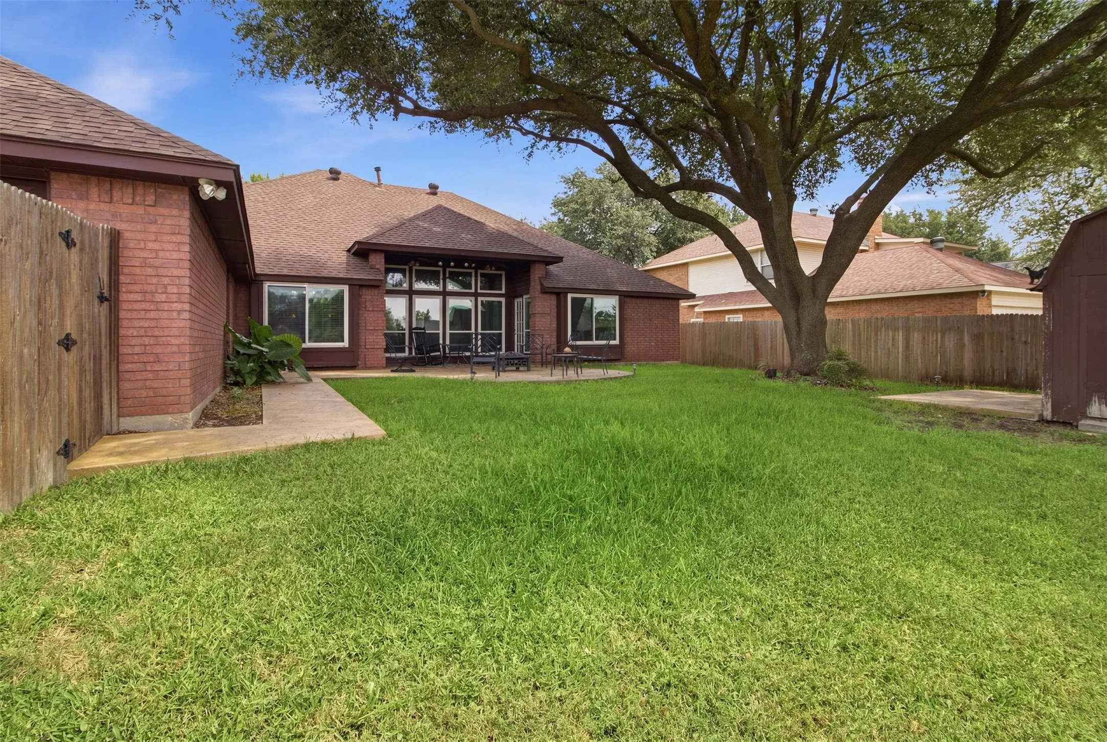 Expansive backyard featuring a large tree, a concrete patio, and a privacy fence