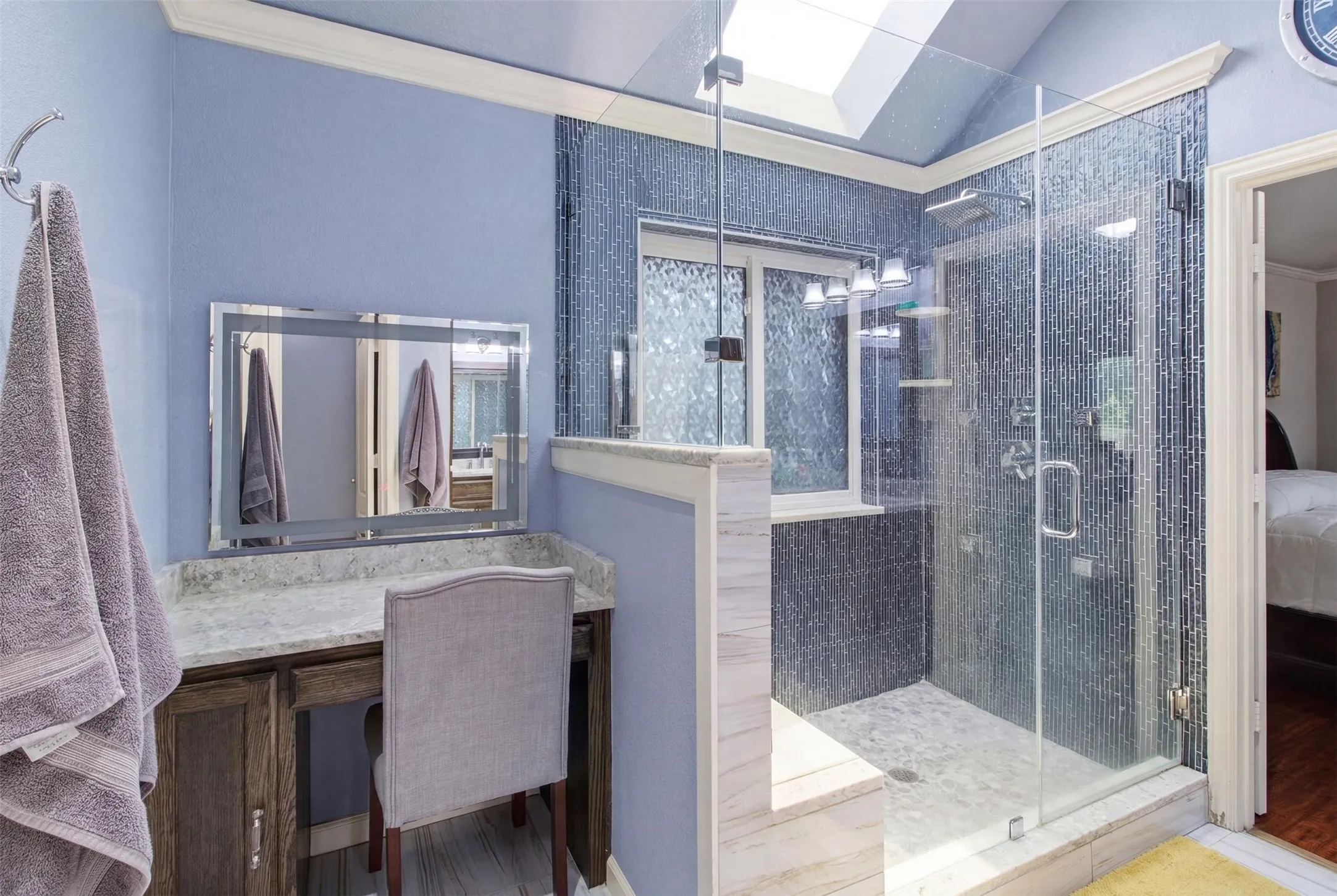 Glass-enclosed shower with mosaic wall tile and a skylight