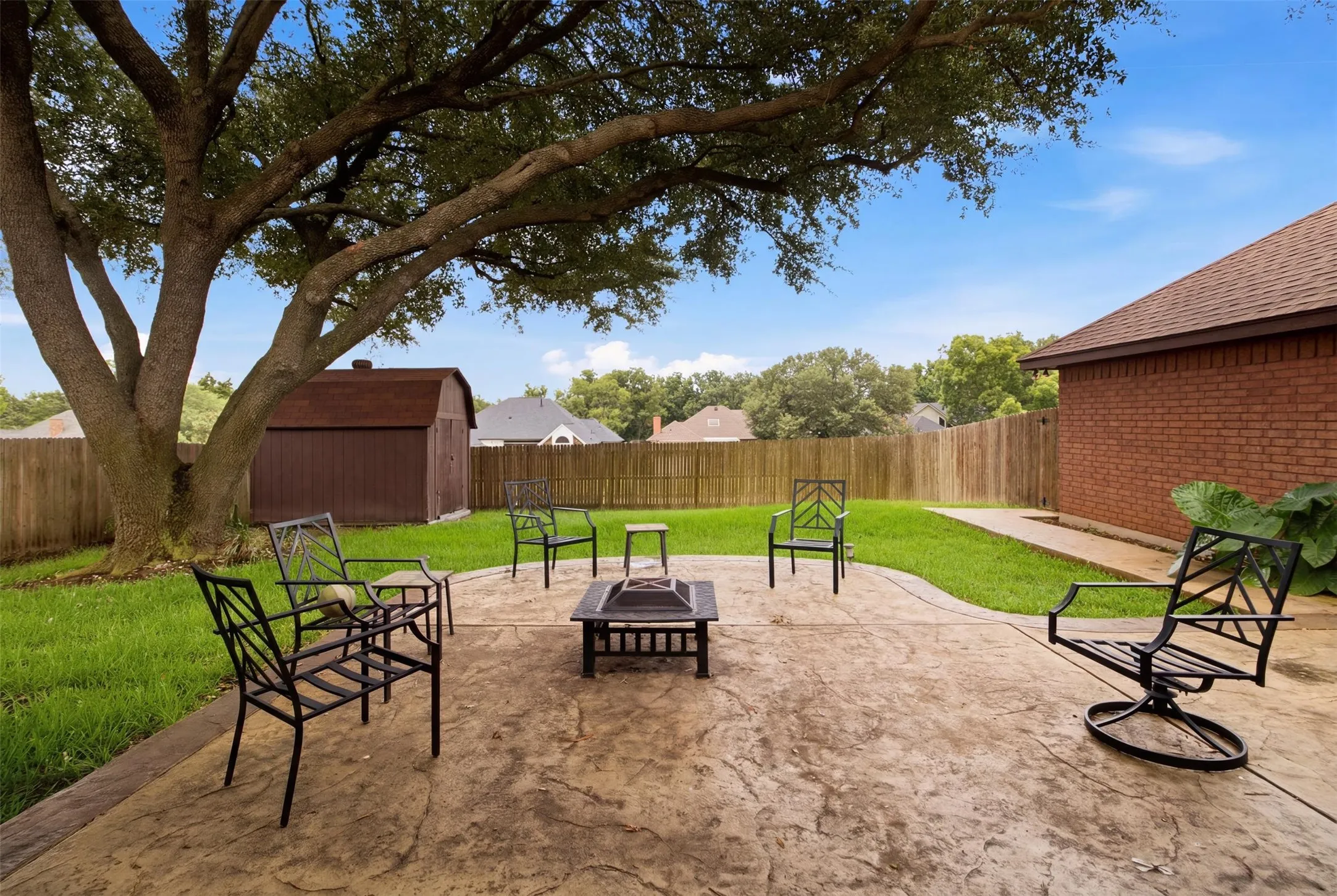 Expansive backyard featuring a stamped concrete patio and a built-in fire pit