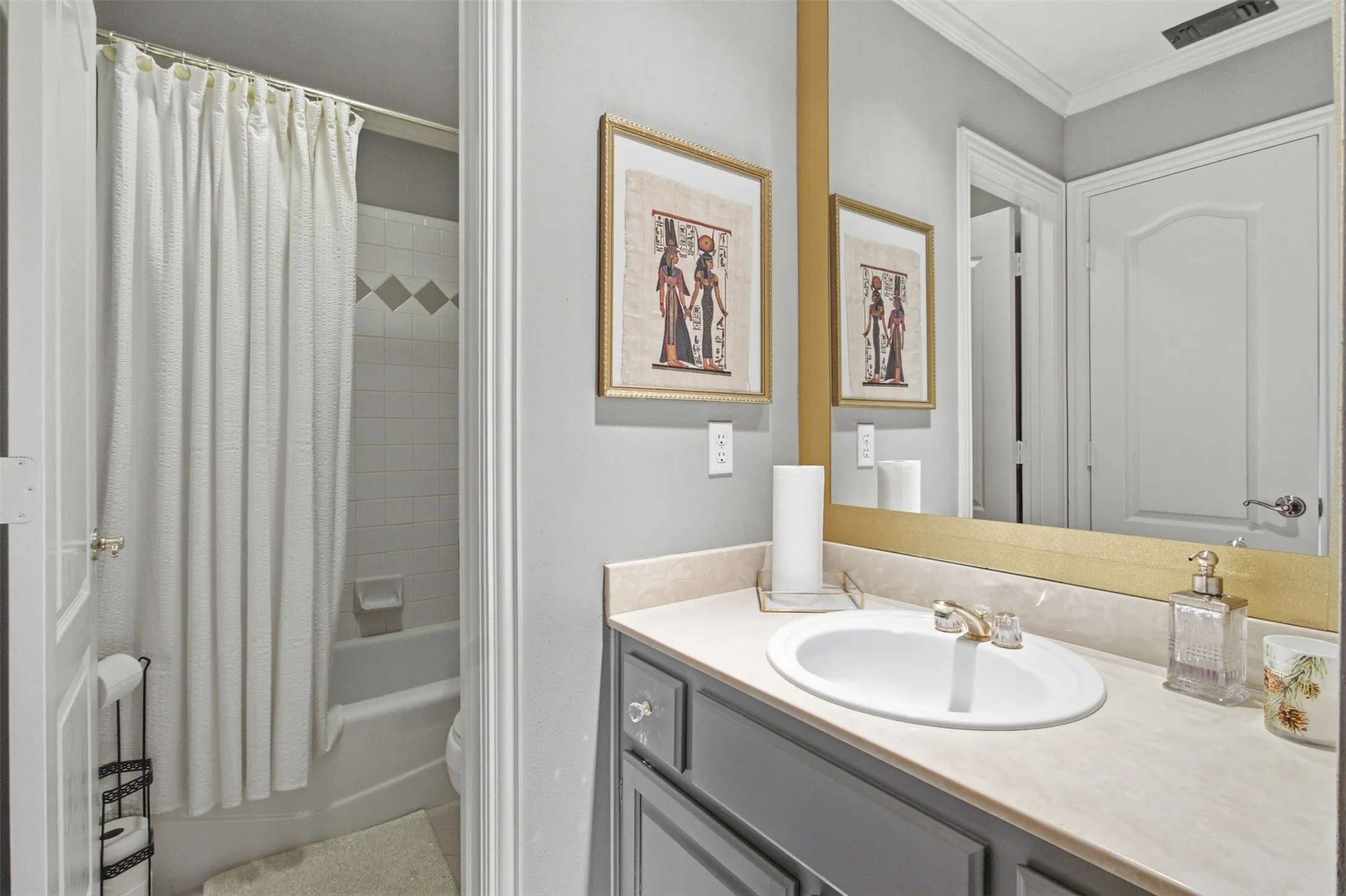 Bathroom featuring a vanity with a light-colored countertop and undermount sink, framed mirror, and a tub/shower combination with white subway tile and decorative diamond-patterned accent tiles