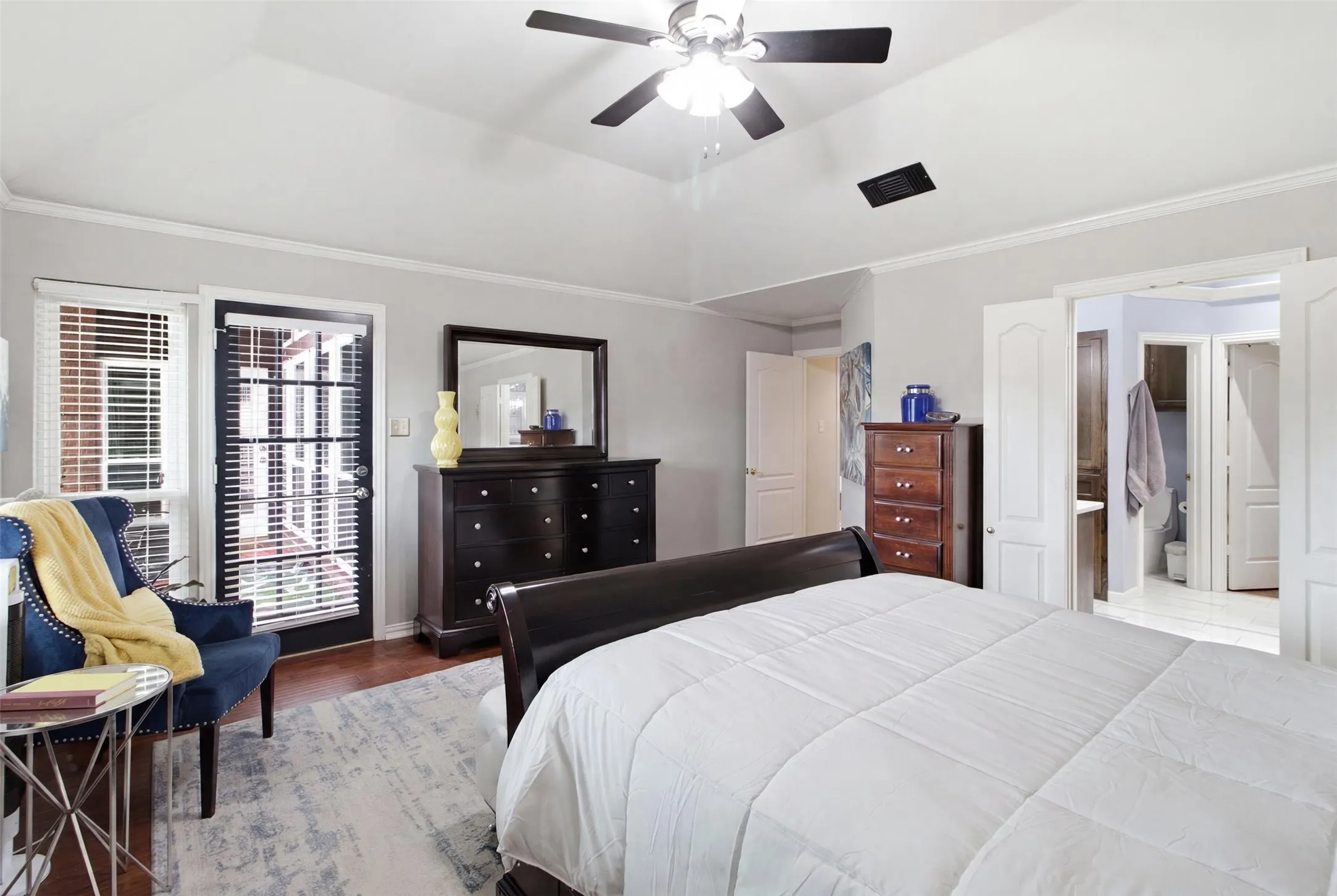 Vaulted ceiling with a ceiling fan, hardwood flooring, crown molding, a French door, and an interior door