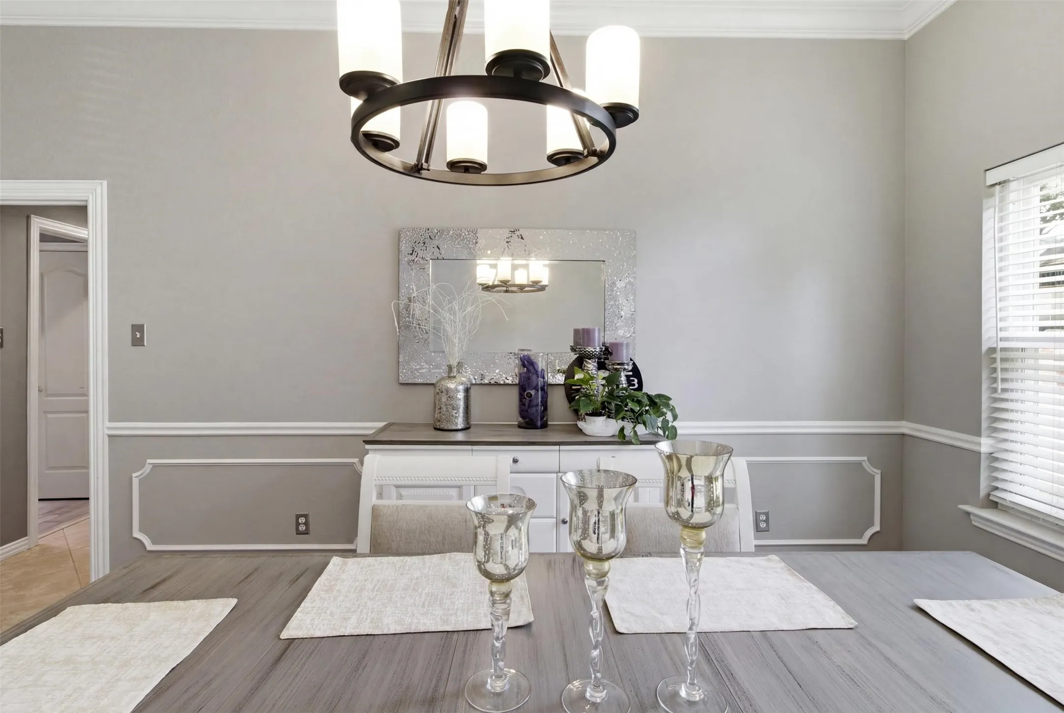 Formal dining area featuring a modern chandelier, crown molding, and wainscoting