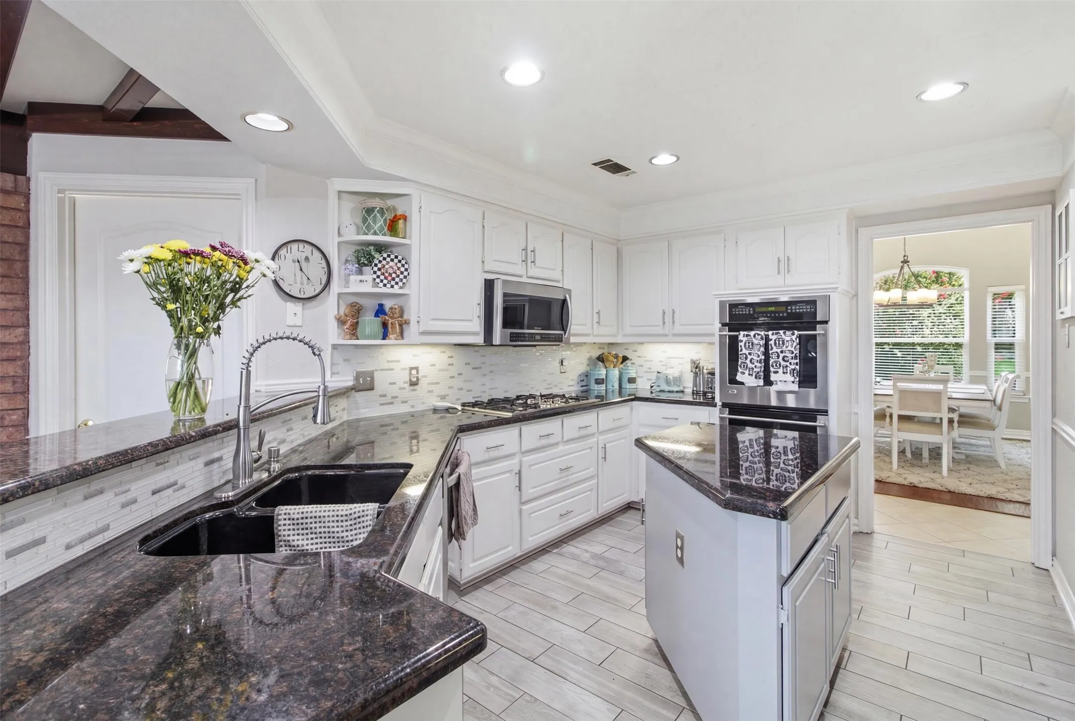 Kitchen featuring white cabinetry, dark granite countertops, stainless steel appliances, a built-in wall oven, and wood-finish tile flooring