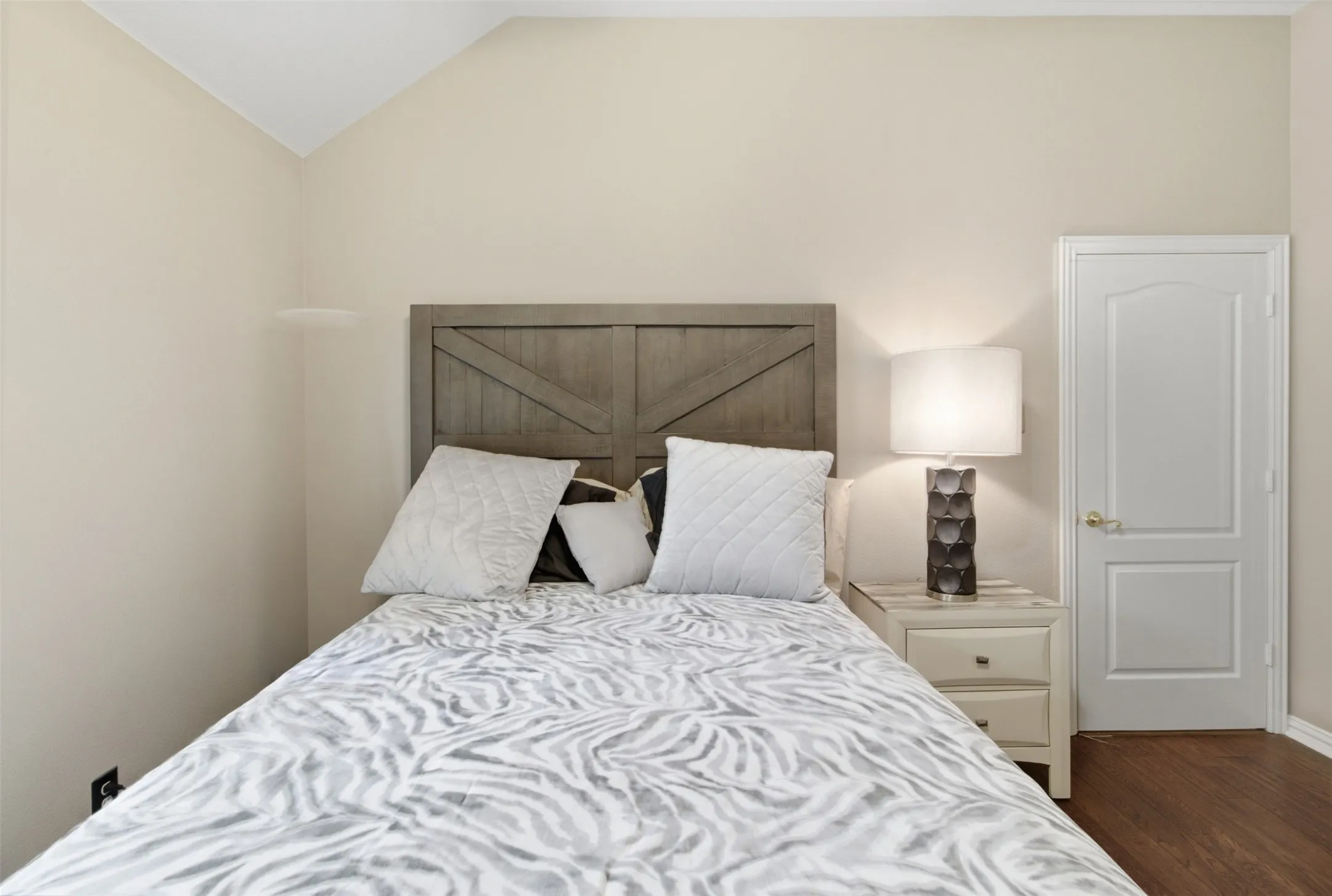 Vaulted ceiling room featuring light-toned walls and wood-finish flooring
