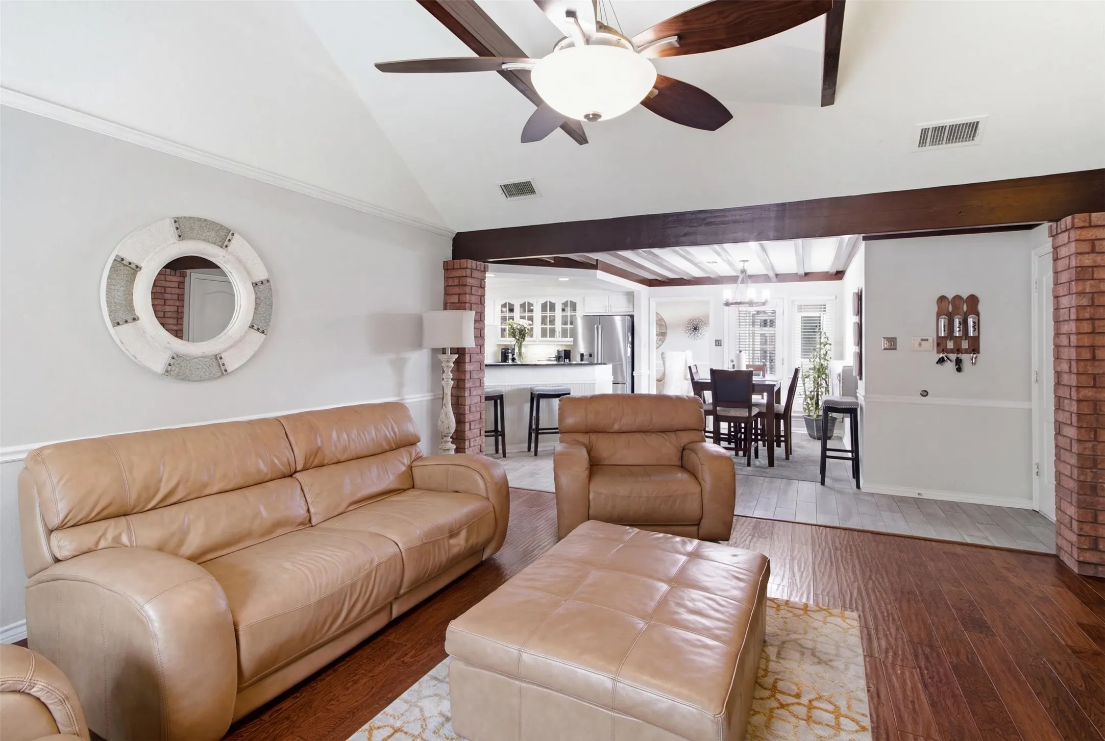 Vaulted ceiling with a ceiling fan and wood-finish beams