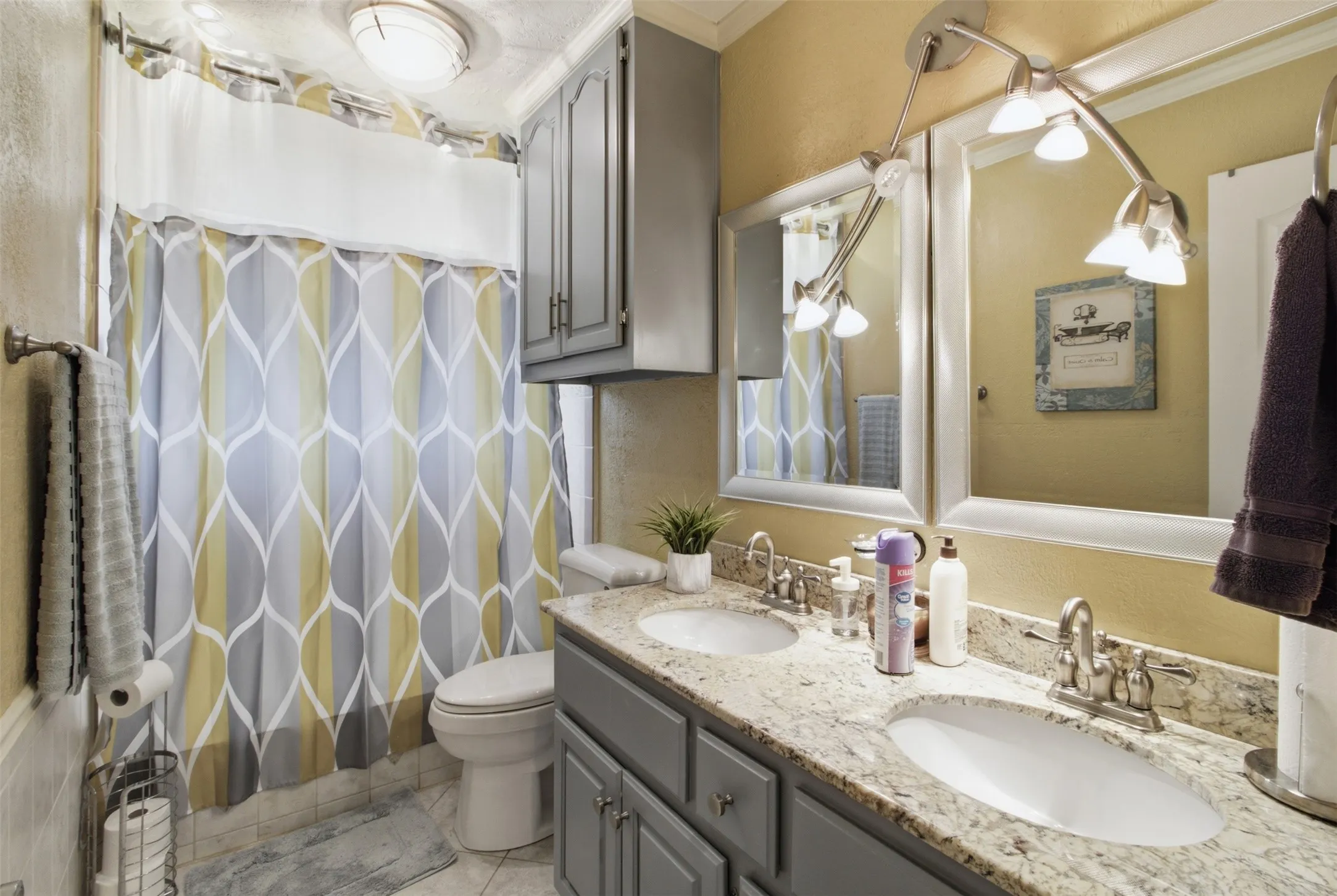 Bathroom featuring a dual-sink vanity with granite-style countertop, white framed mirrors, and track lighting