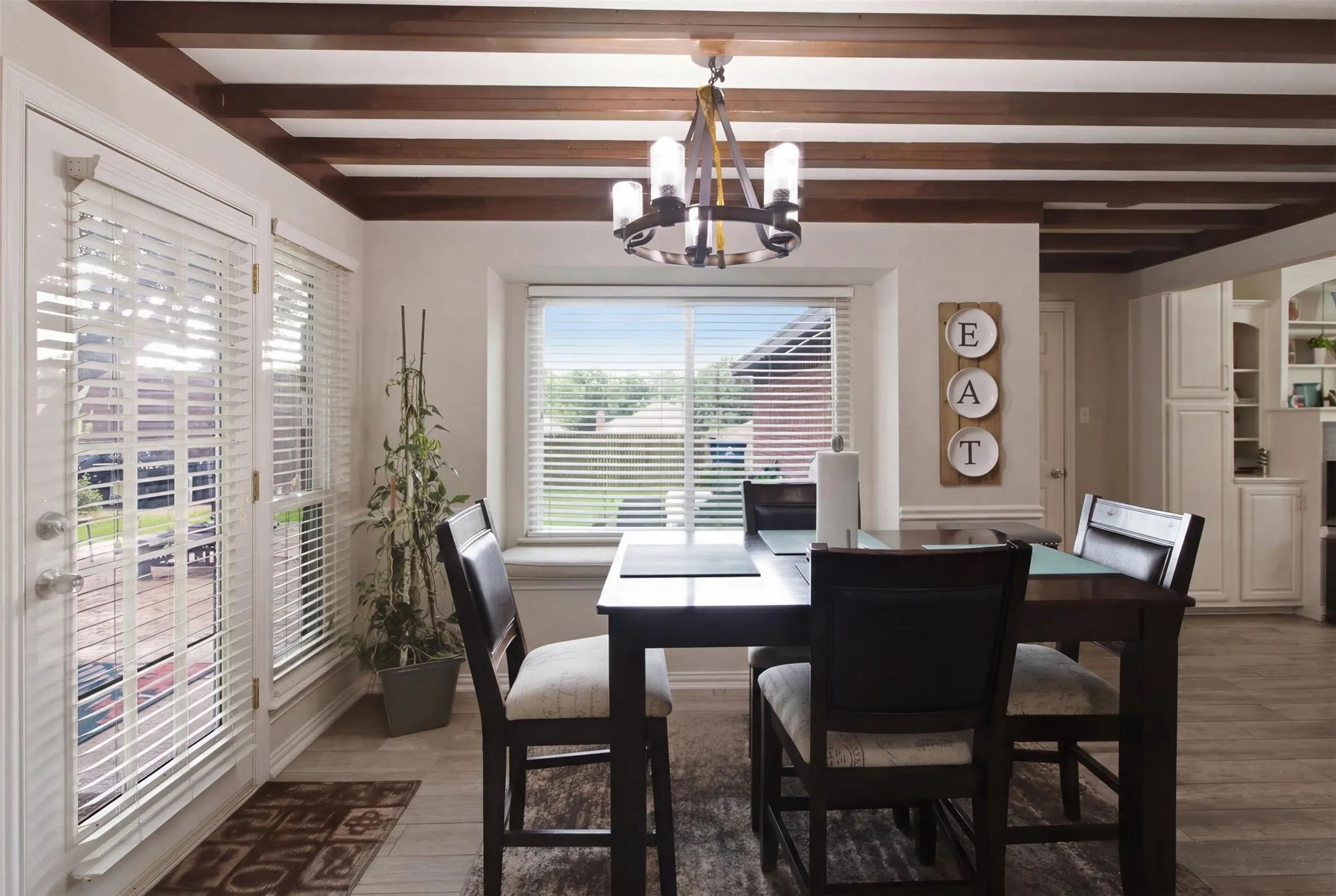 Dining area featuring exposed ceiling beams, wood-finish flooring, and a contemporary chandelier