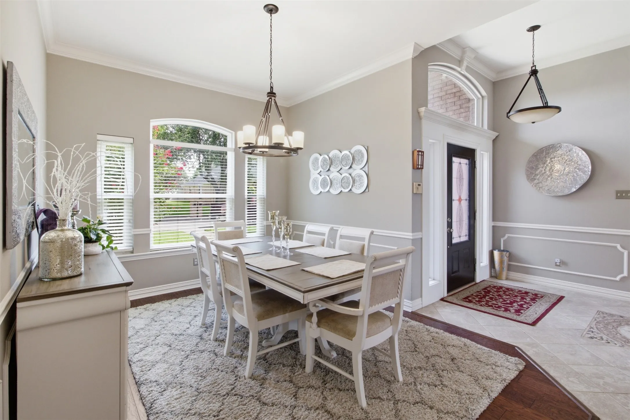 Formal dining area featuring a prominent arched window and a chandelier with candle-style lights