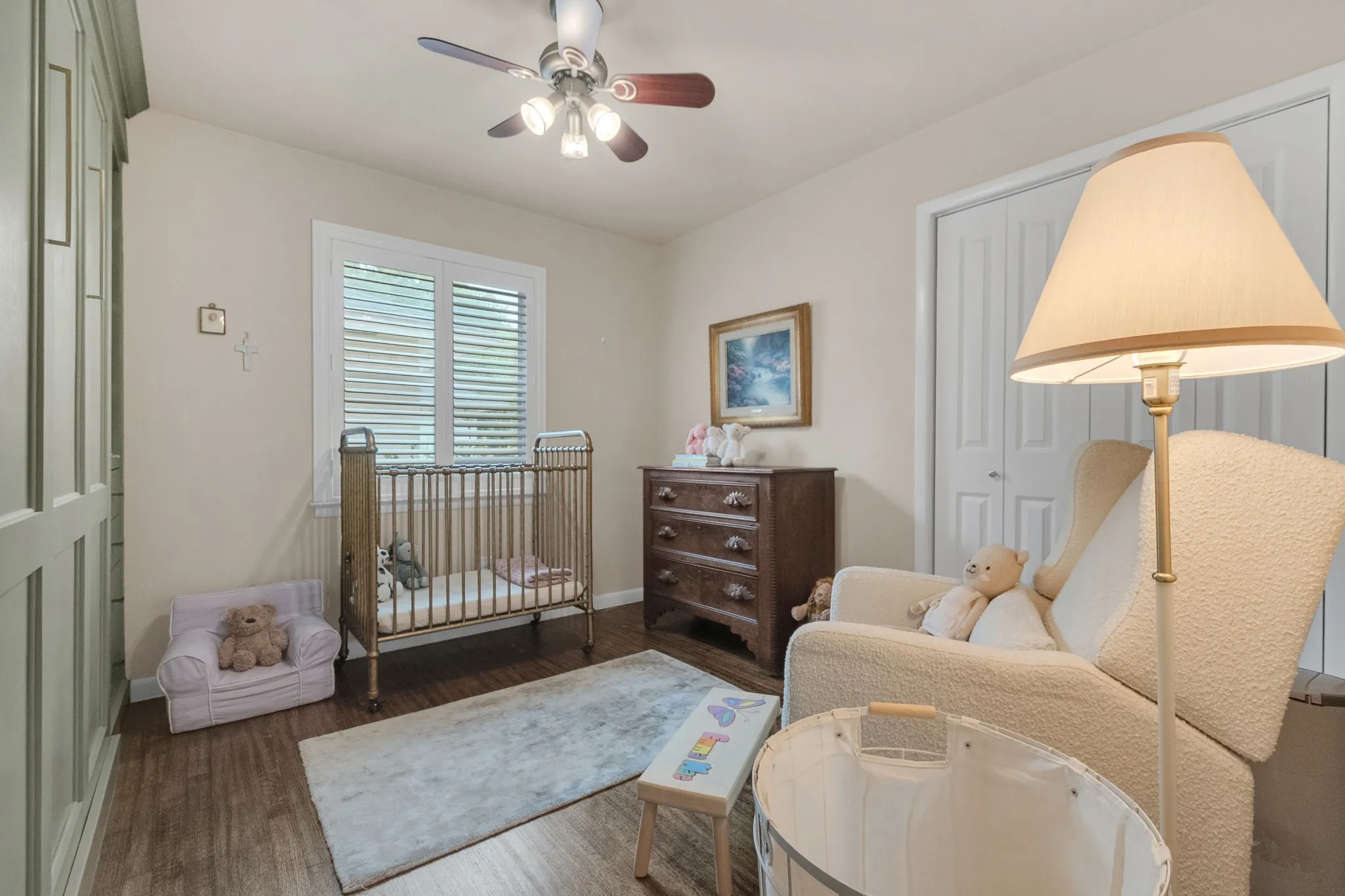 Room featuring wood-finish flooring, a ceiling fan with integrated lighting, and a window with plantation shutters
