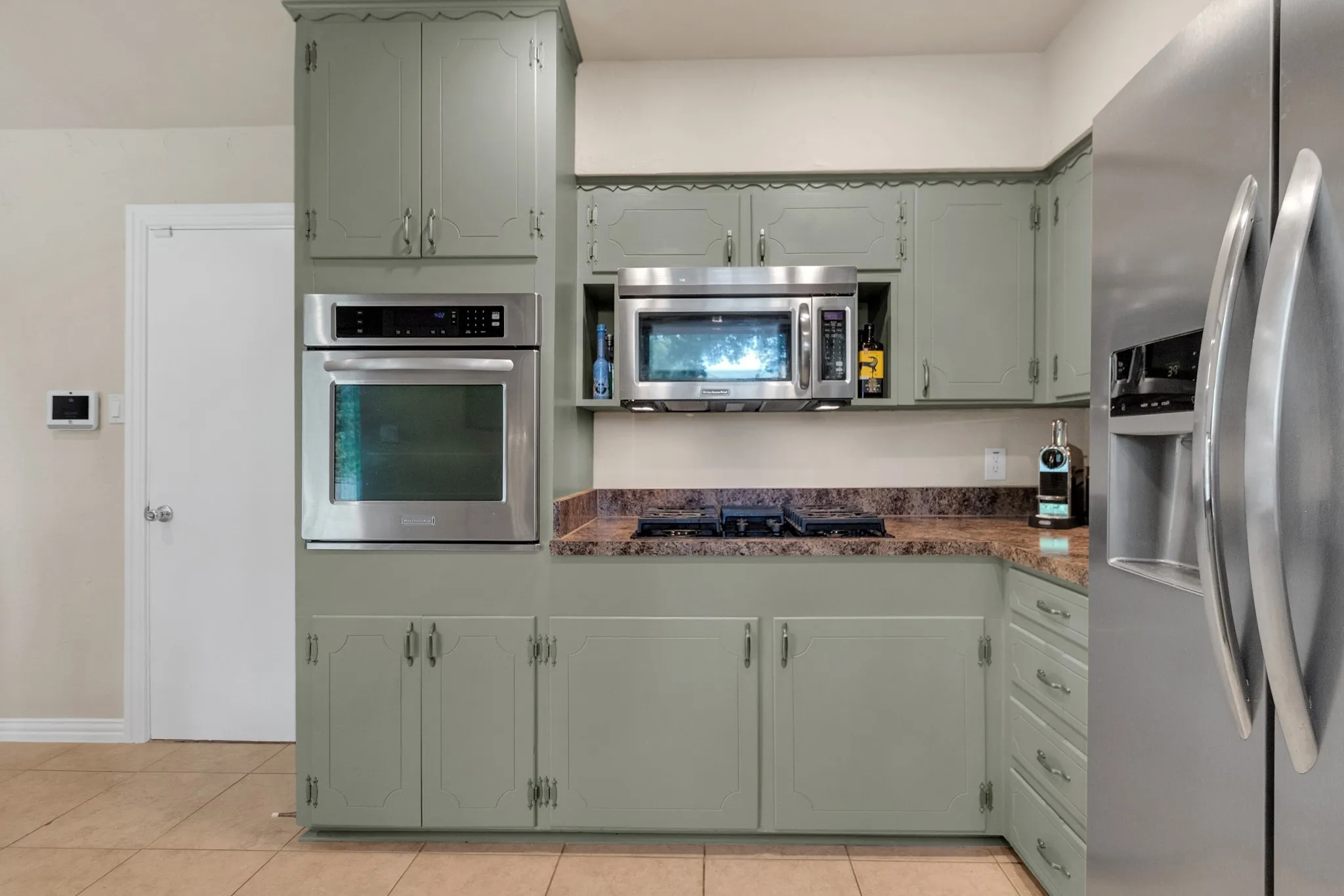 Kitchen featuring wood-finish cabinetry, built-in stainless steel oven, integrated microwave, cooktop, and stone-finish countertops