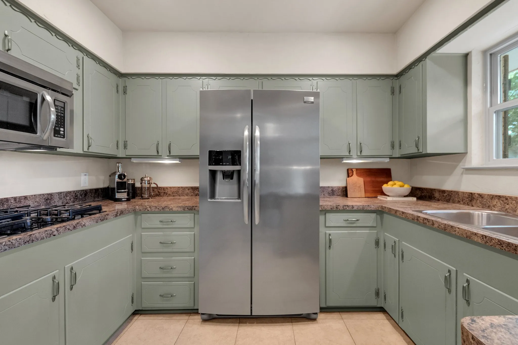 Spacious kitchen featuring sage green cabinetry, a stainless steel side-by-side refrigerator, a built-in microwave, and a double basin stainless steel sink