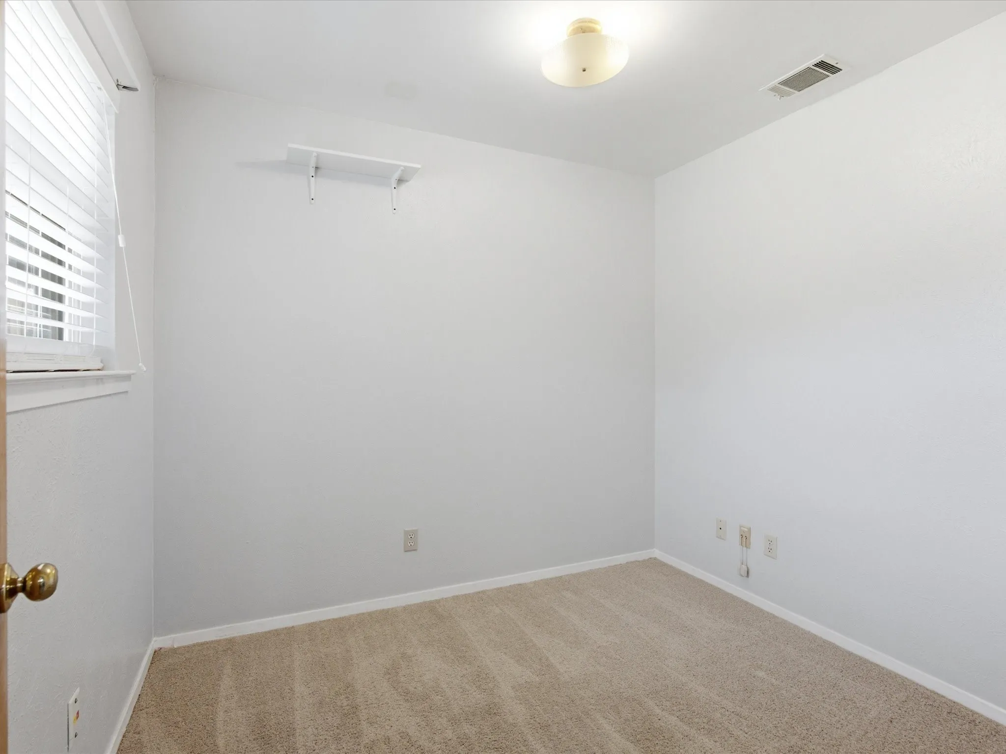 Carpeted room with a window, white walls, and a built-in shelf