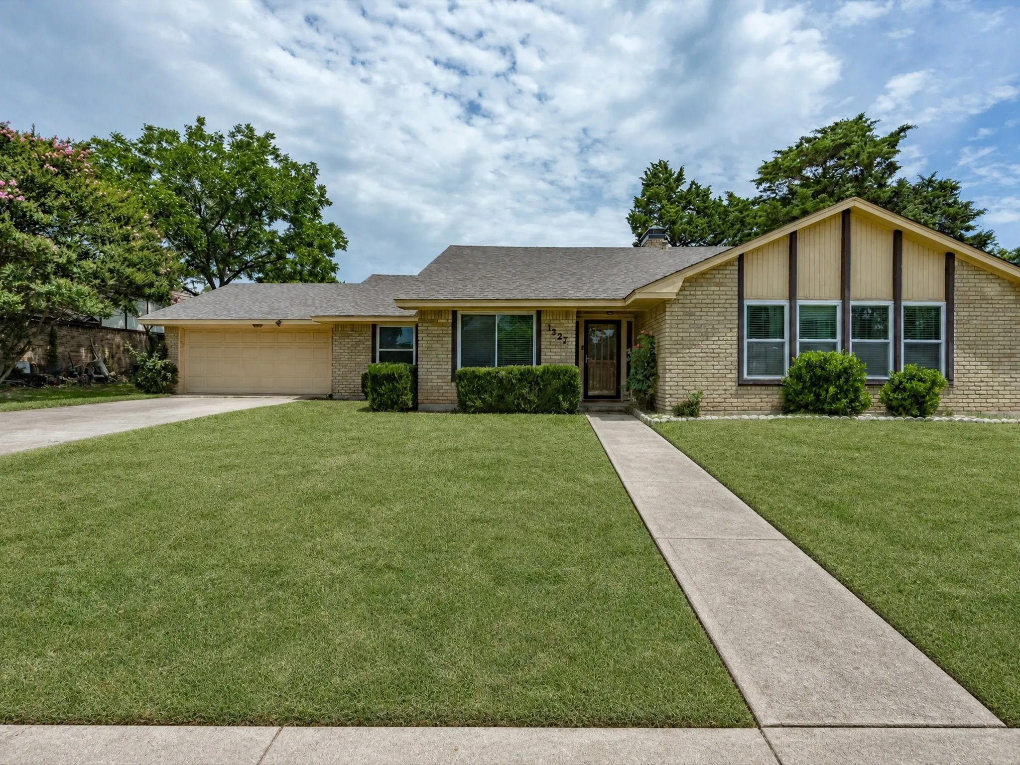 Single-story brick residence featuring a two-car garage, a concrete driveway, and a front walkway leading to the entry