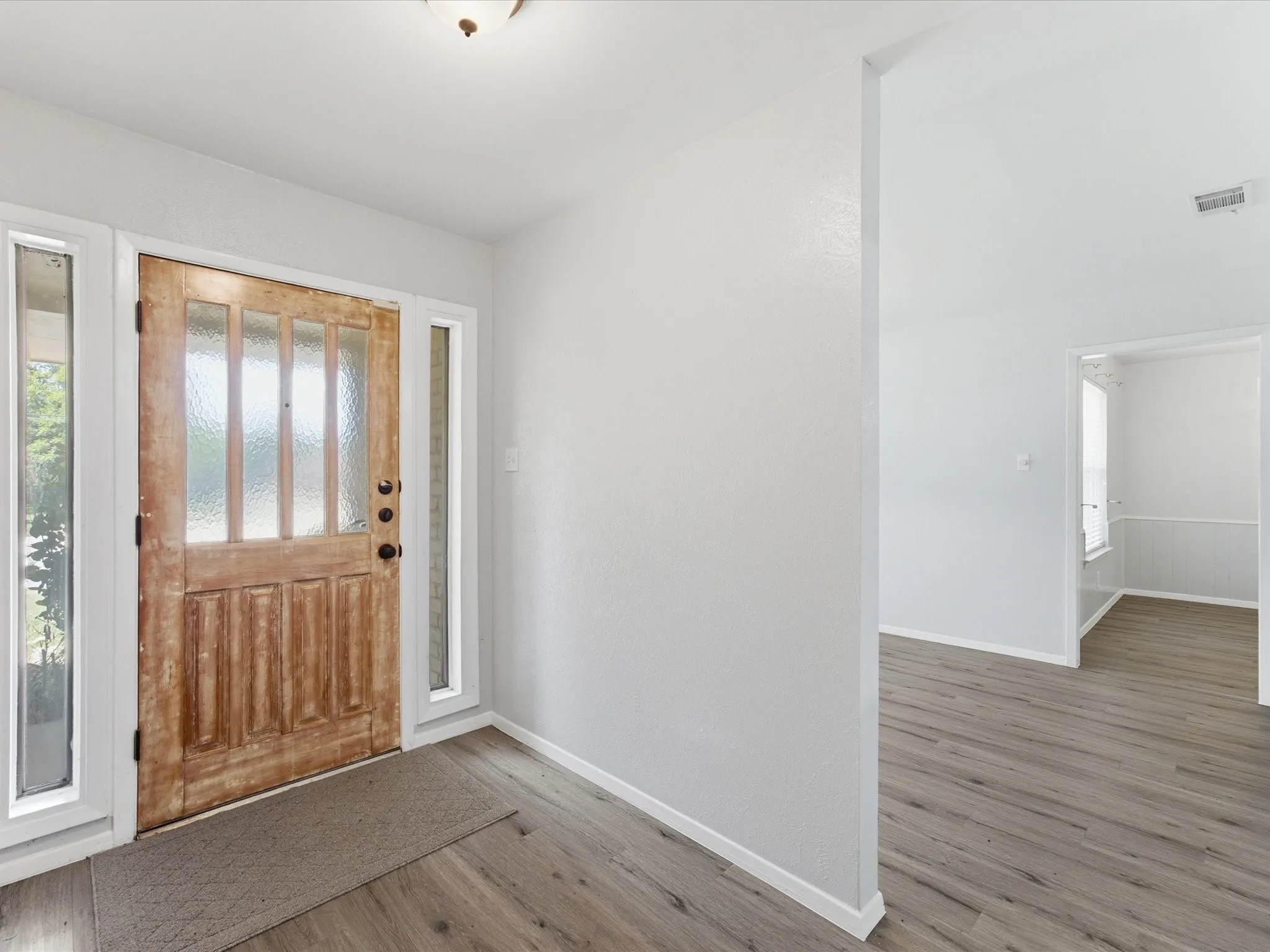 Entryway featuring a paneled wood-finish door with frosted glass inserts, flanked by clear glass sidelights