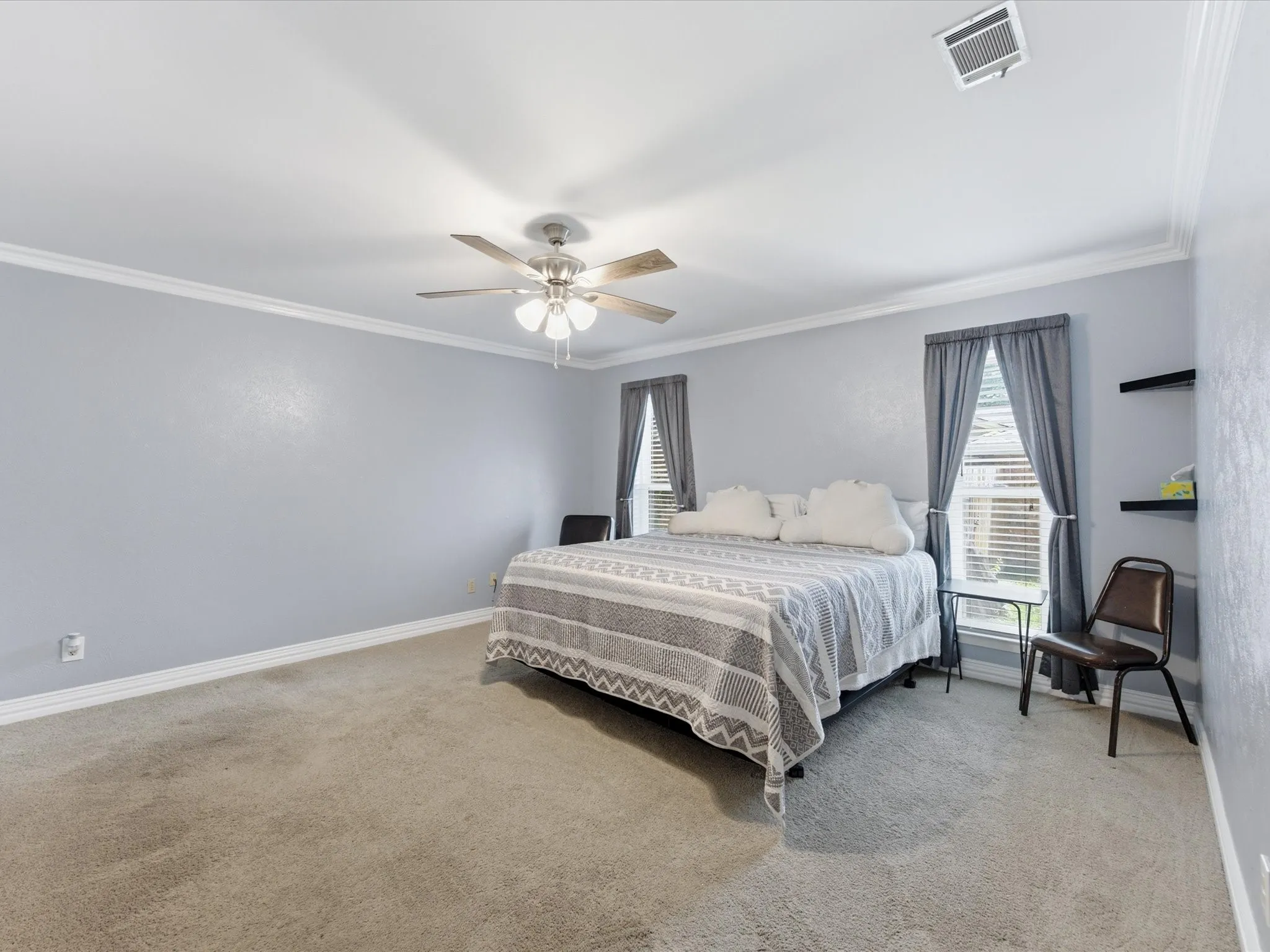 Spacious room featuring light gray walls, crown molding, and neutral carpet