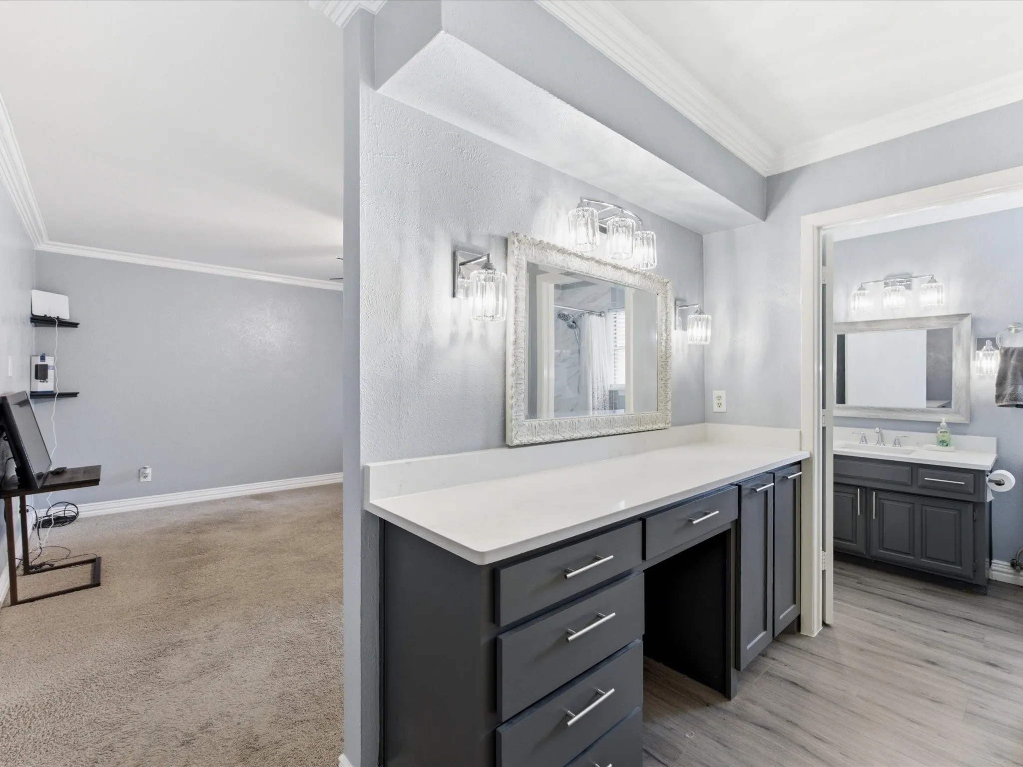 Vanity area featuring a white countertop, dark cabinetry with silver hardware, and a framed mirror with decorative sconces