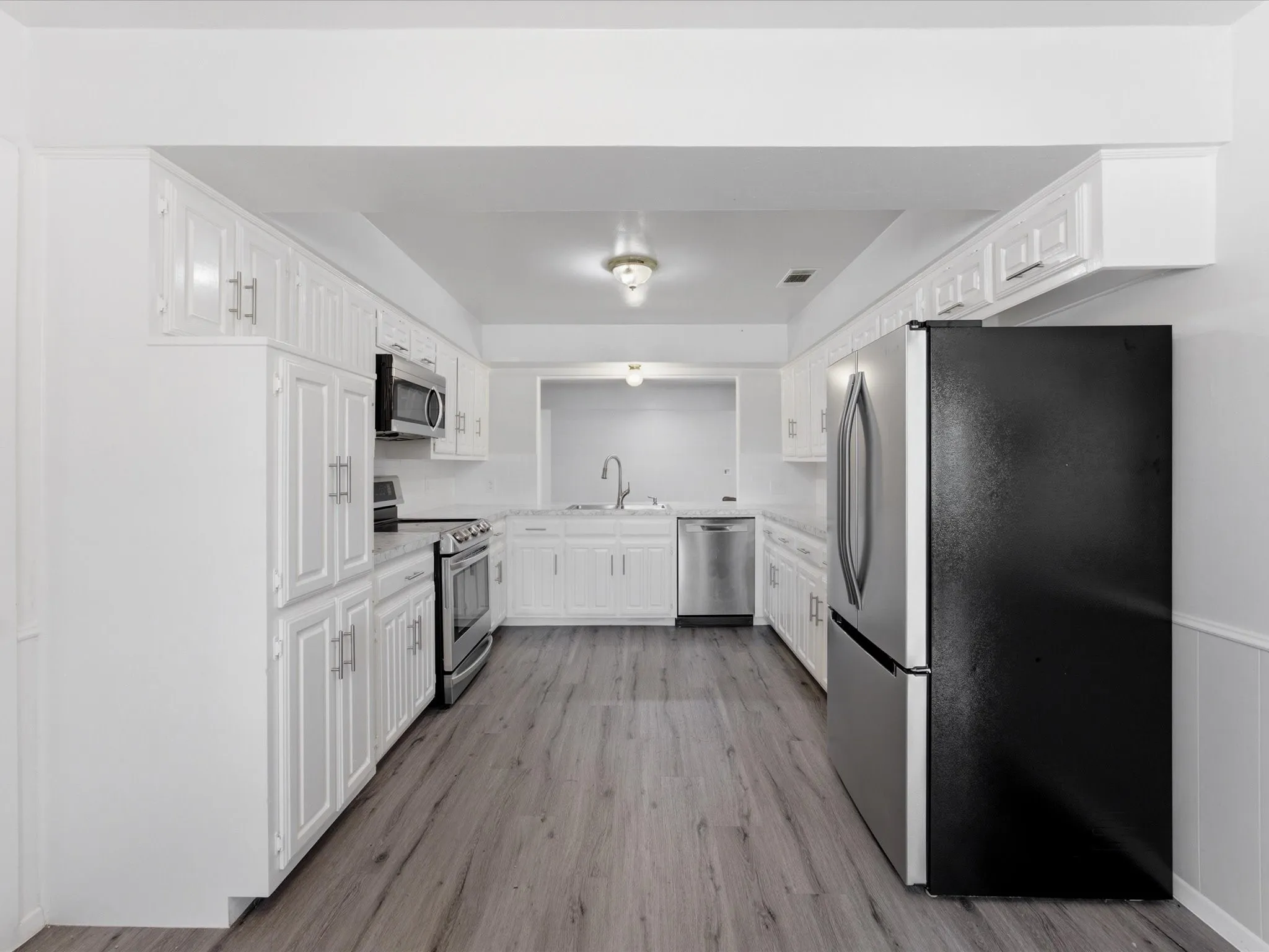 Bright kitchen with white cabinetry and wood-finish flooring