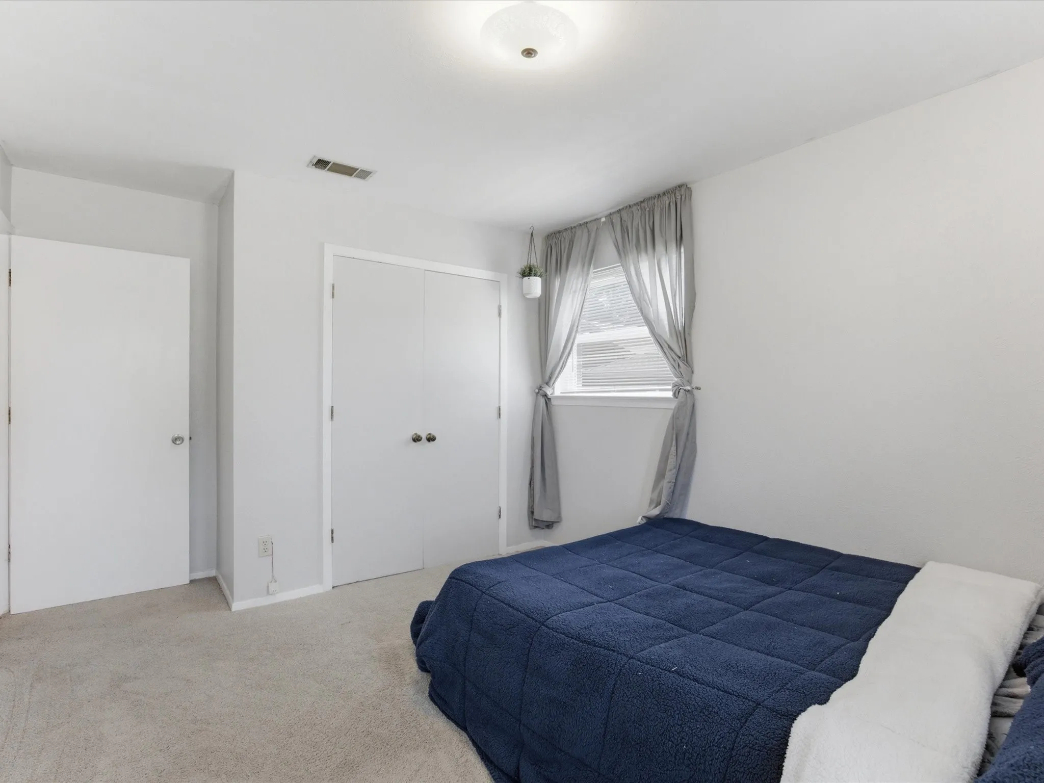 Carpeted room featuring a window with natural light, a ceiling-mounted light fixture, and two white doors
