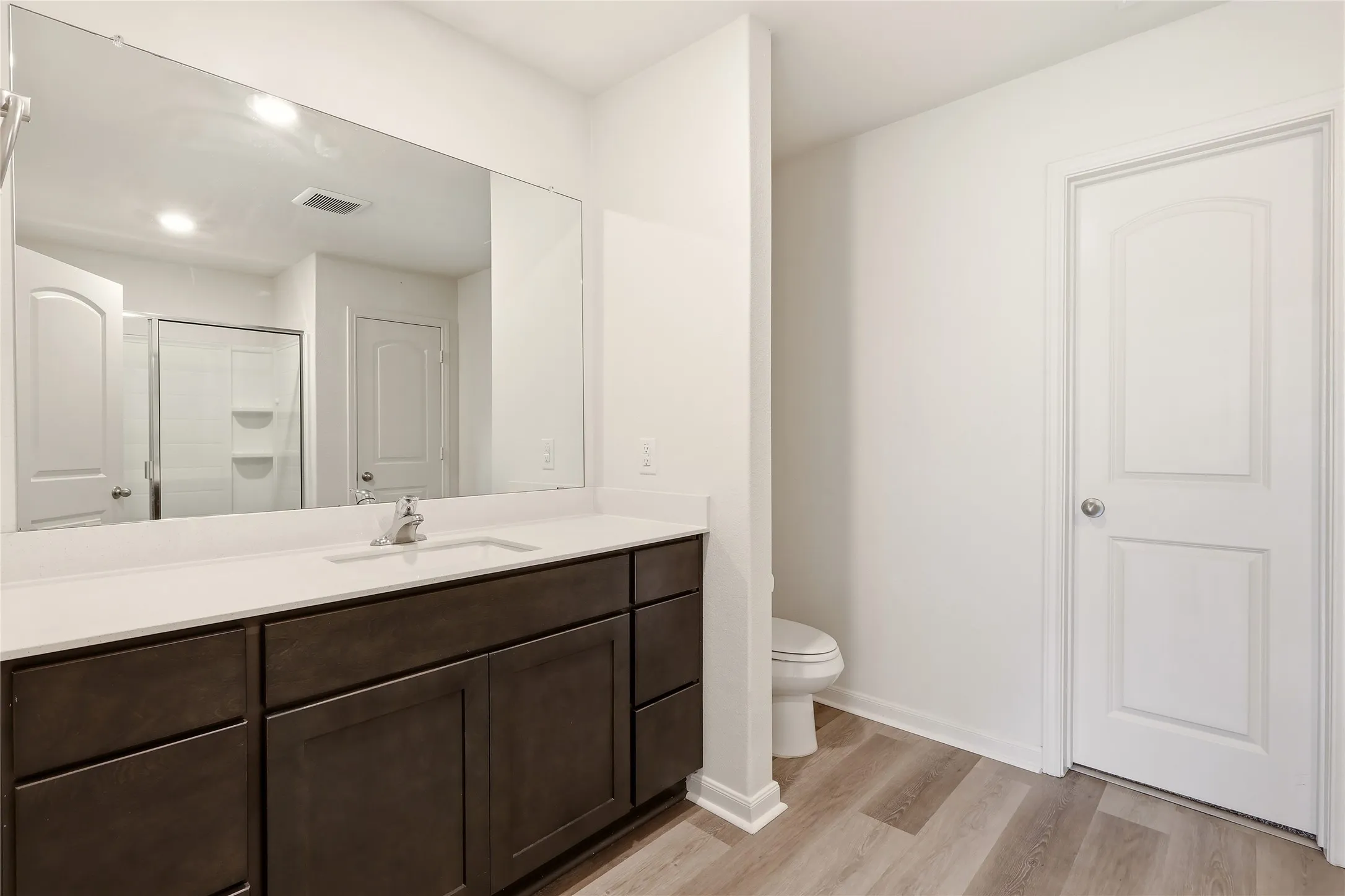 Primary Bathroom featuring vanity with dark wood-finish cabinetry, and a large wall-mounted mirror.