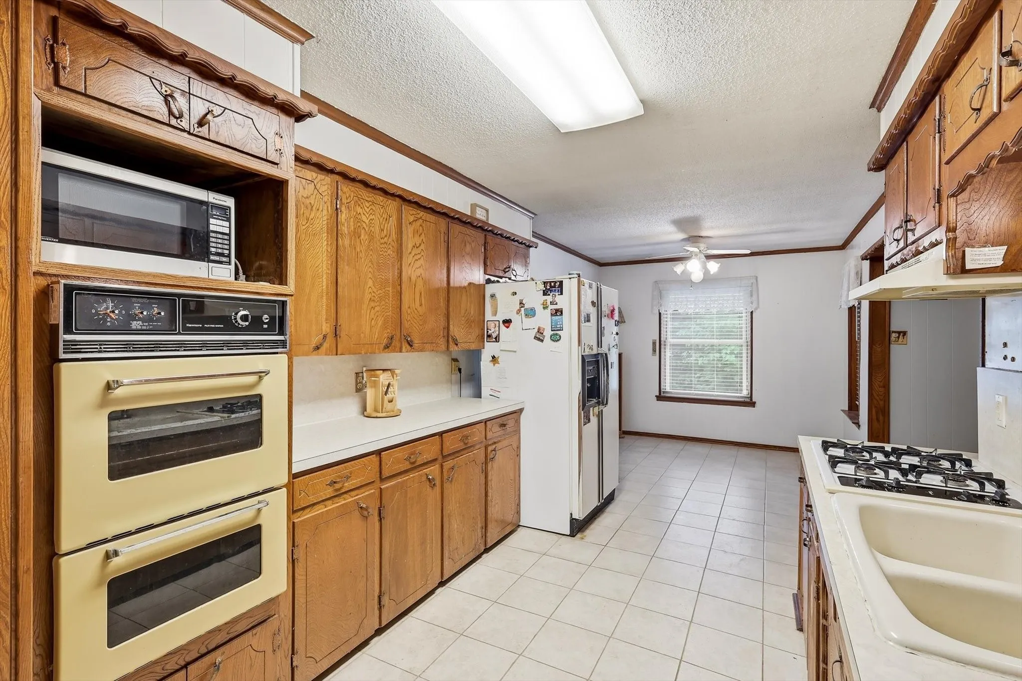 Kitchen featuring wood cabinetry, white countertops, tile flooring, and white paneled walls