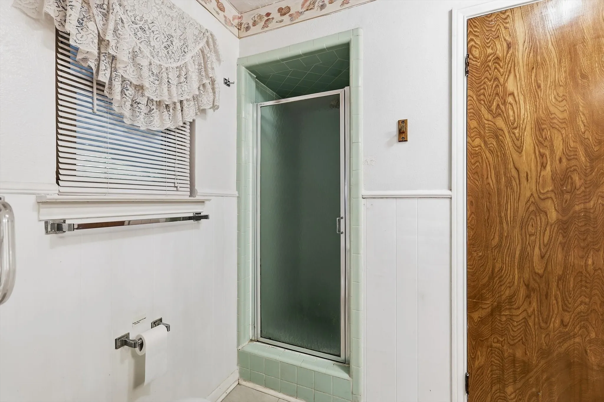 Bathroom featuring a shower enclosure with a frosted glass door and green tile surround