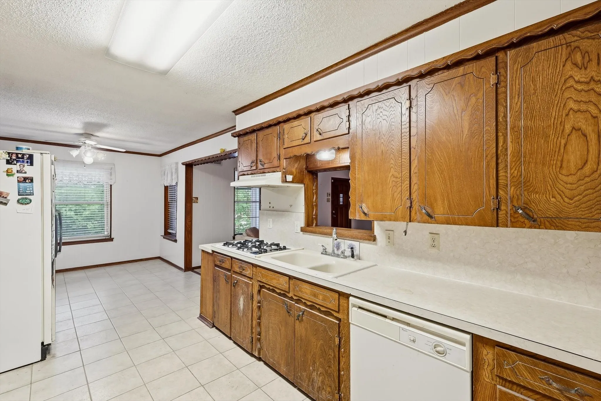 Kitchen featuring wood cabinetry, white countertops, a built-in gas range, and a white dishwasher