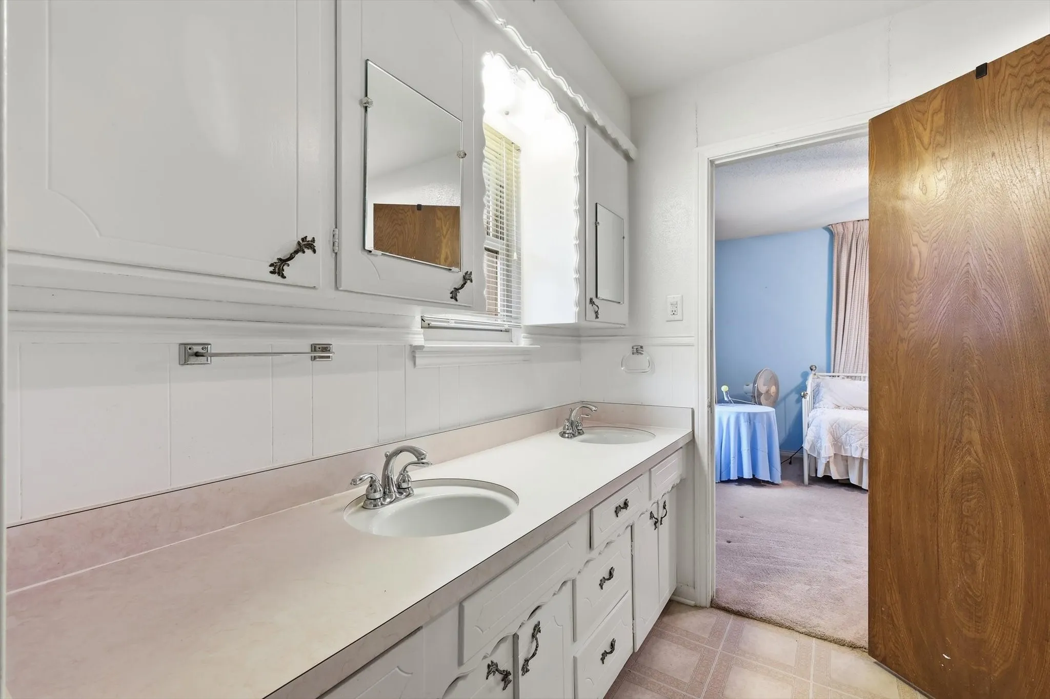 Dual basin vanity with white cabinetry, integrated sinks, chrome fixtures, and overhead mirrored medicine cabinets